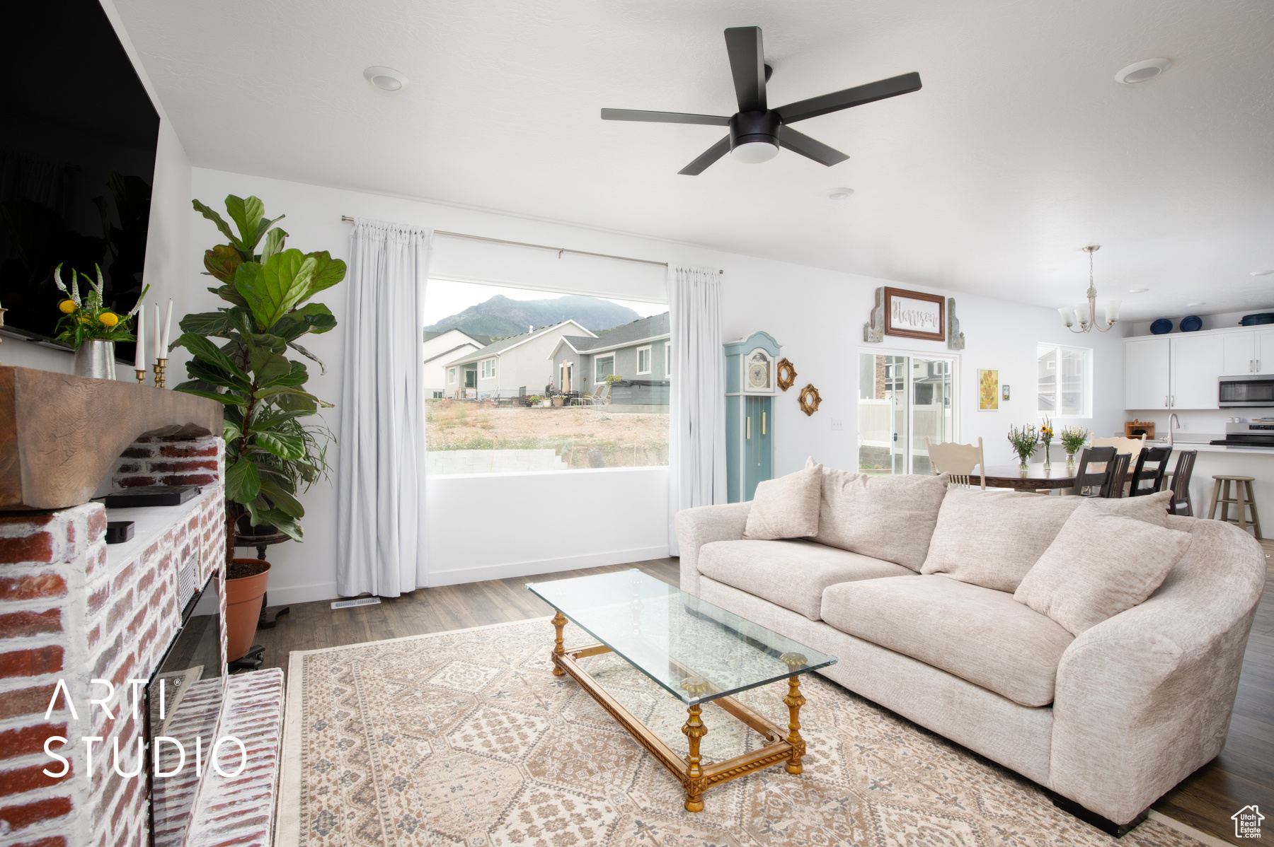 Living room featuring a wealth of natural light, light hardwood / wood-style floors, ceiling fan with notable chandelier, and a fireplace