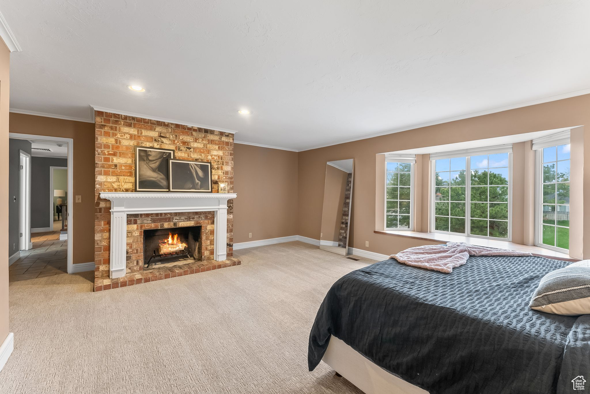 Carpeted bedroom with a brick fireplace and crown molding