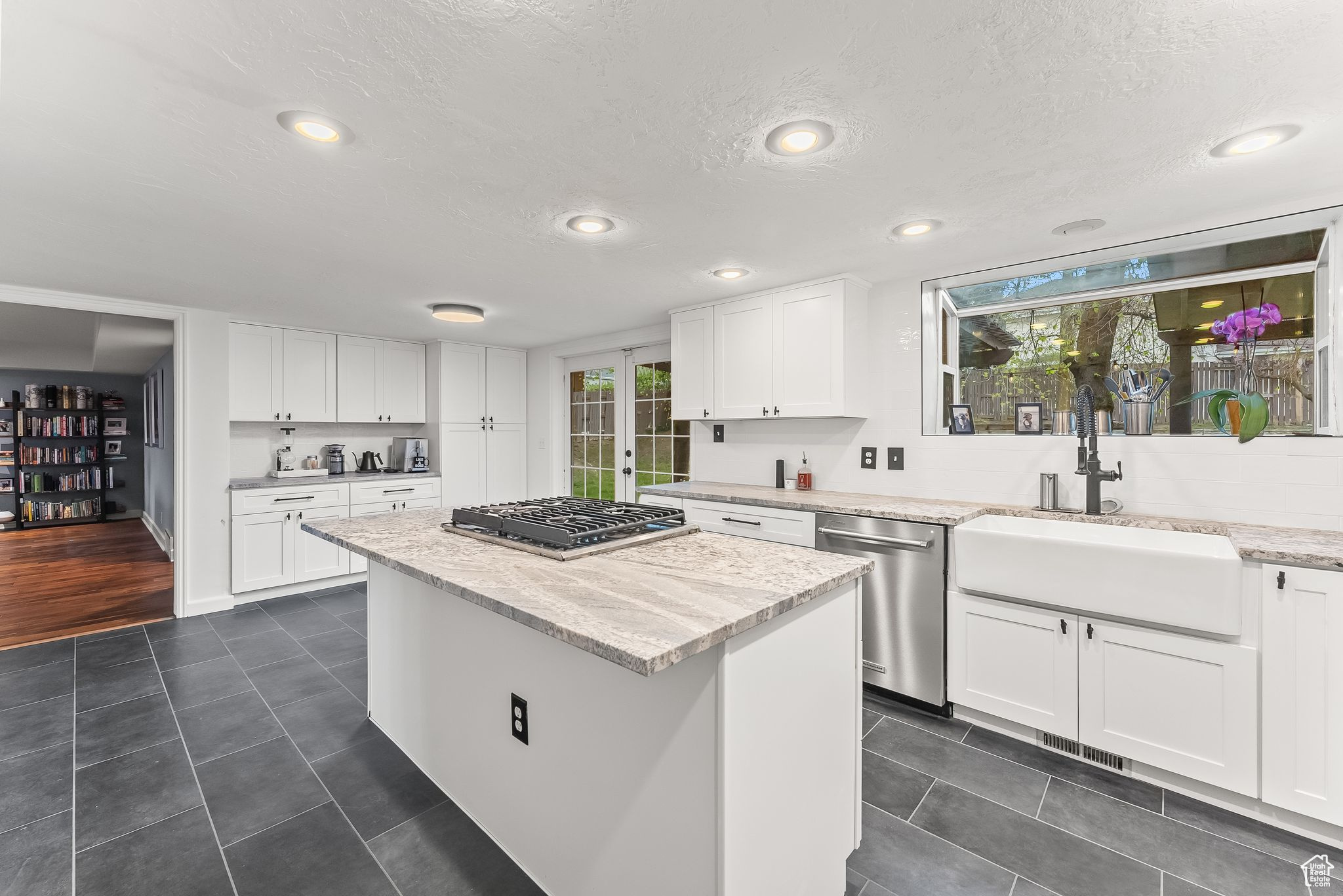 Kitchen featuring white cabinets, sink, stainless steel appliances, and dark tile flooring