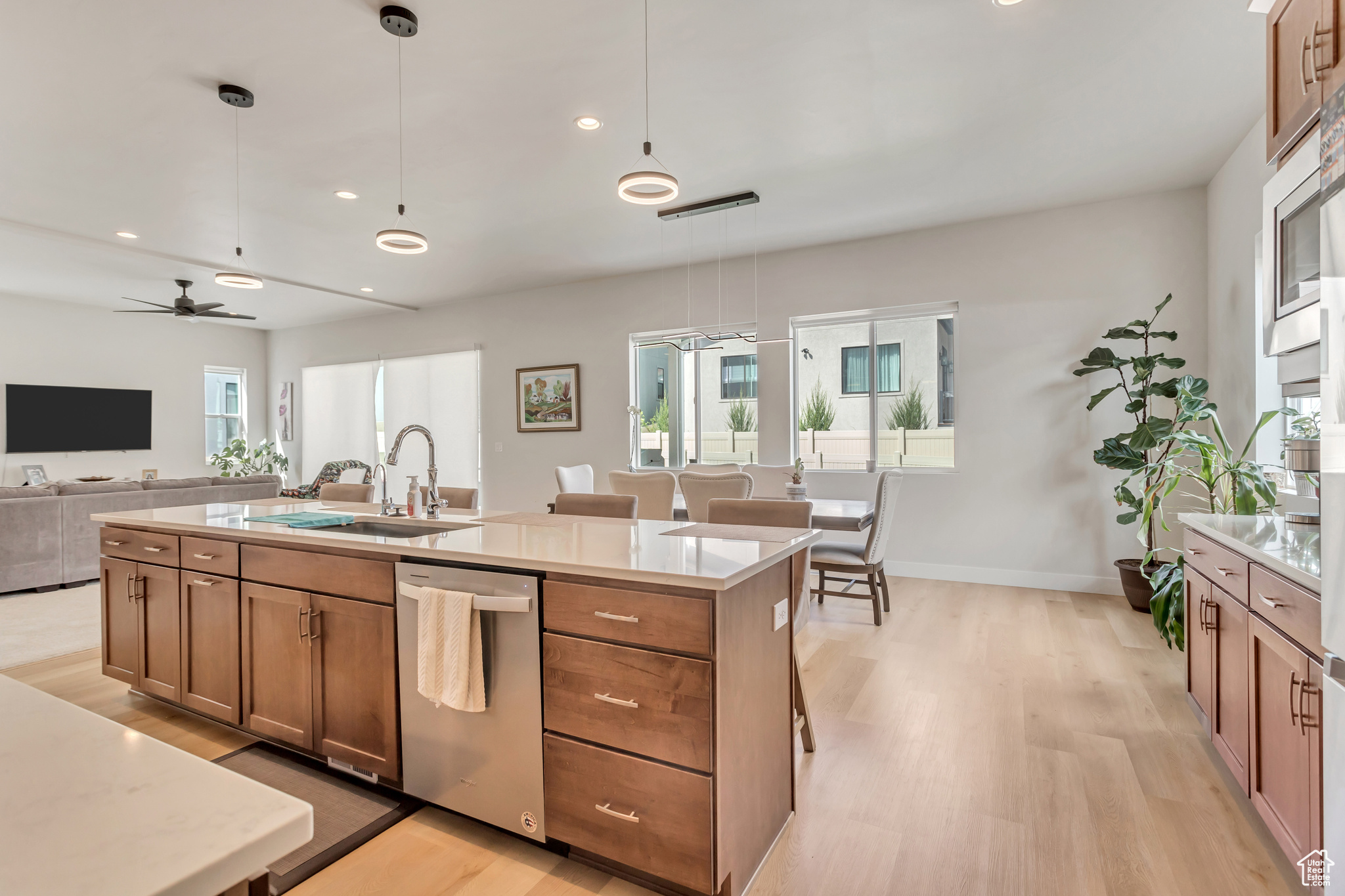 Kitchen featuring light hardwood / wood-style flooring, pendant lighting, dishwasher, and a center island with sink