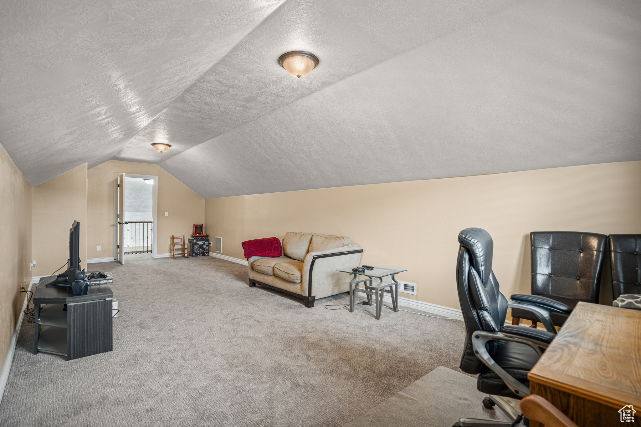 Office with vaulted ceiling, carpet flooring, and a textured ceiling