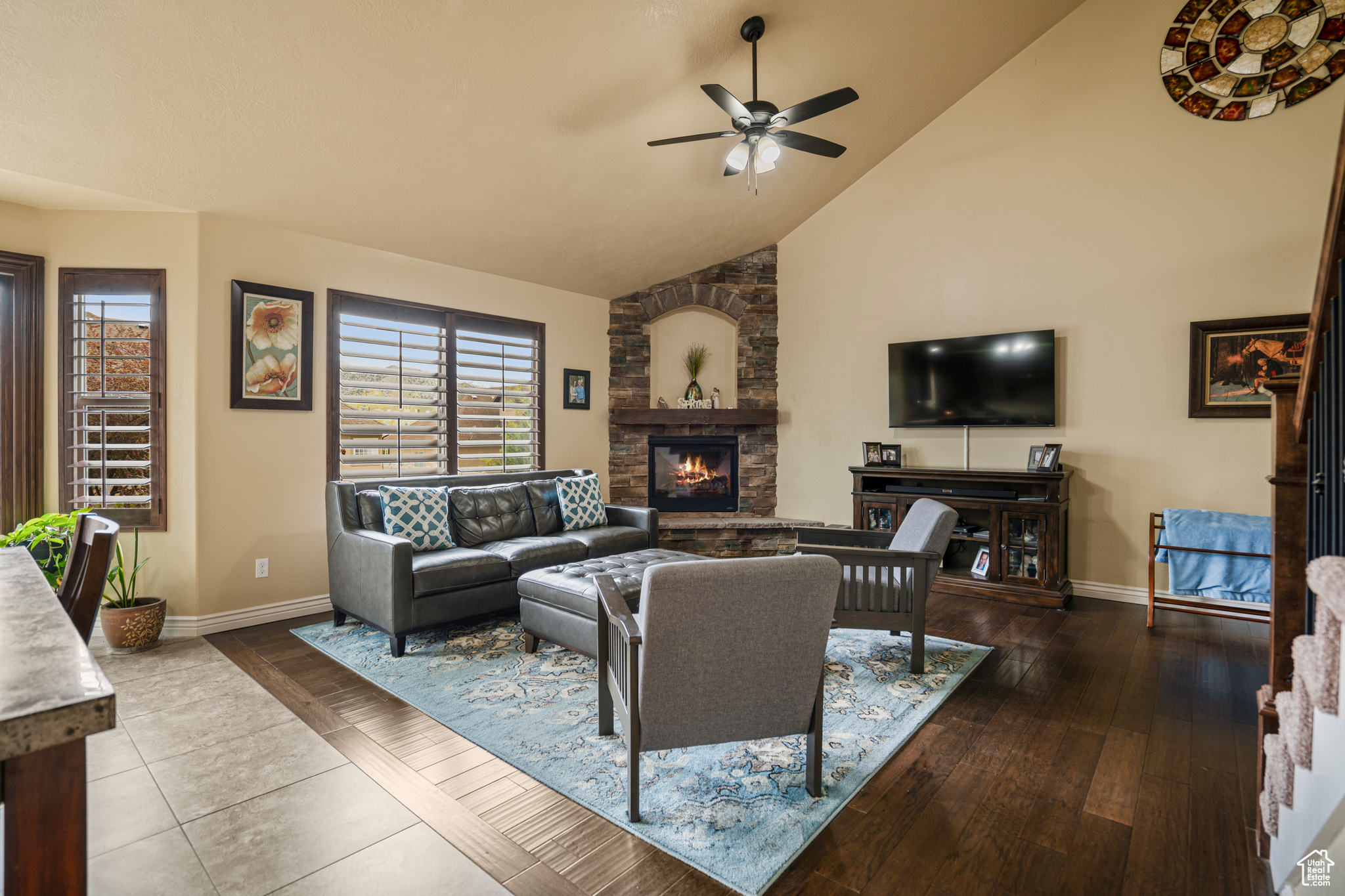 Living room featuring high vaulted ceiling, tile flooring, ceiling fan, and a fireplace