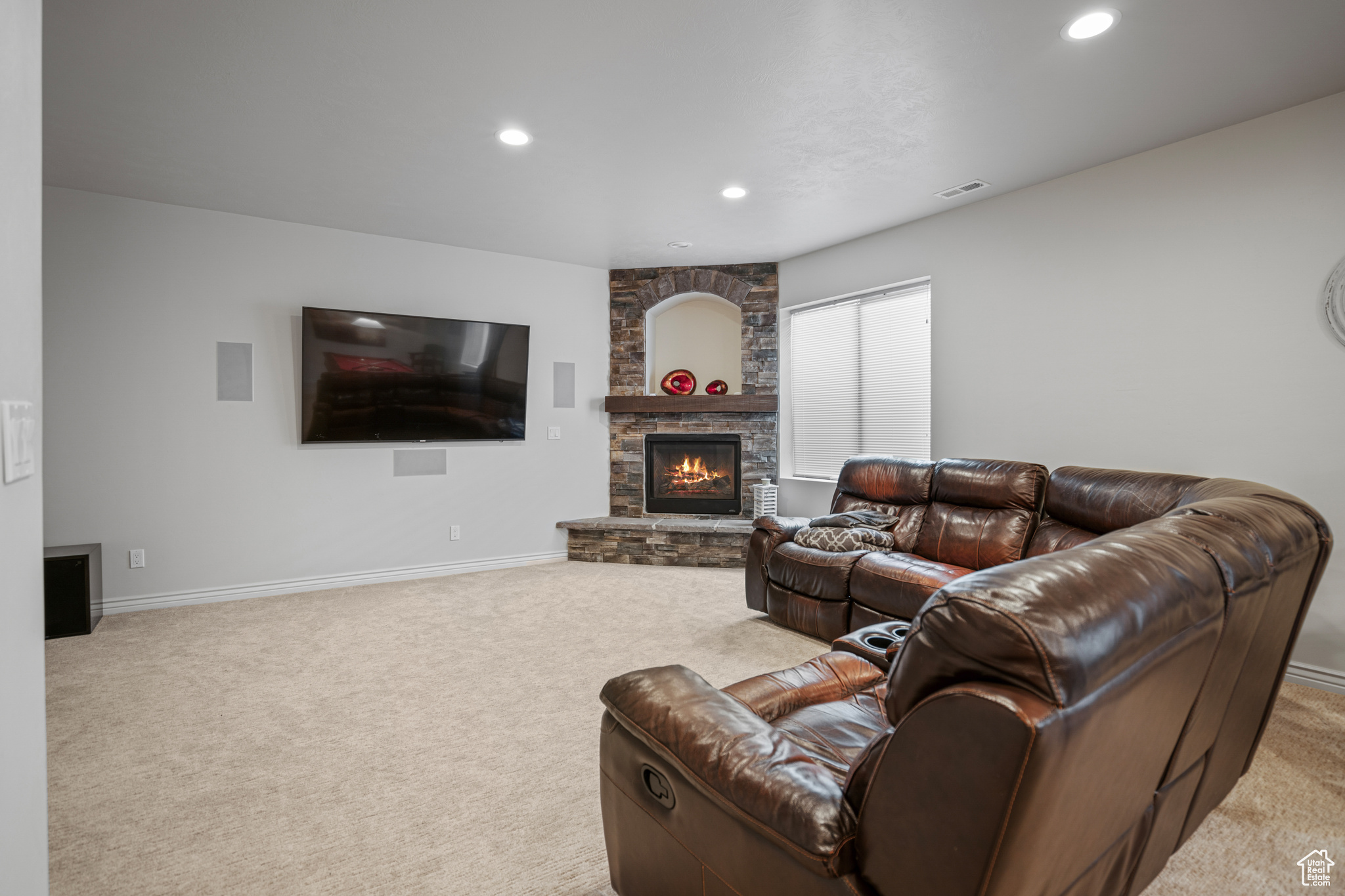 Carpeted living room with a stone fireplace