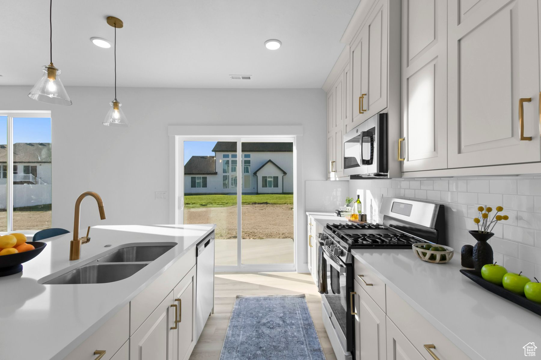 Kitchen featuring white cabinets, backsplash, stainless steel appliances, sink, and light hardwood / wood-style floors