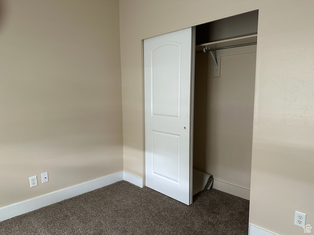 Interior space featuring a closet and dark colored carpet