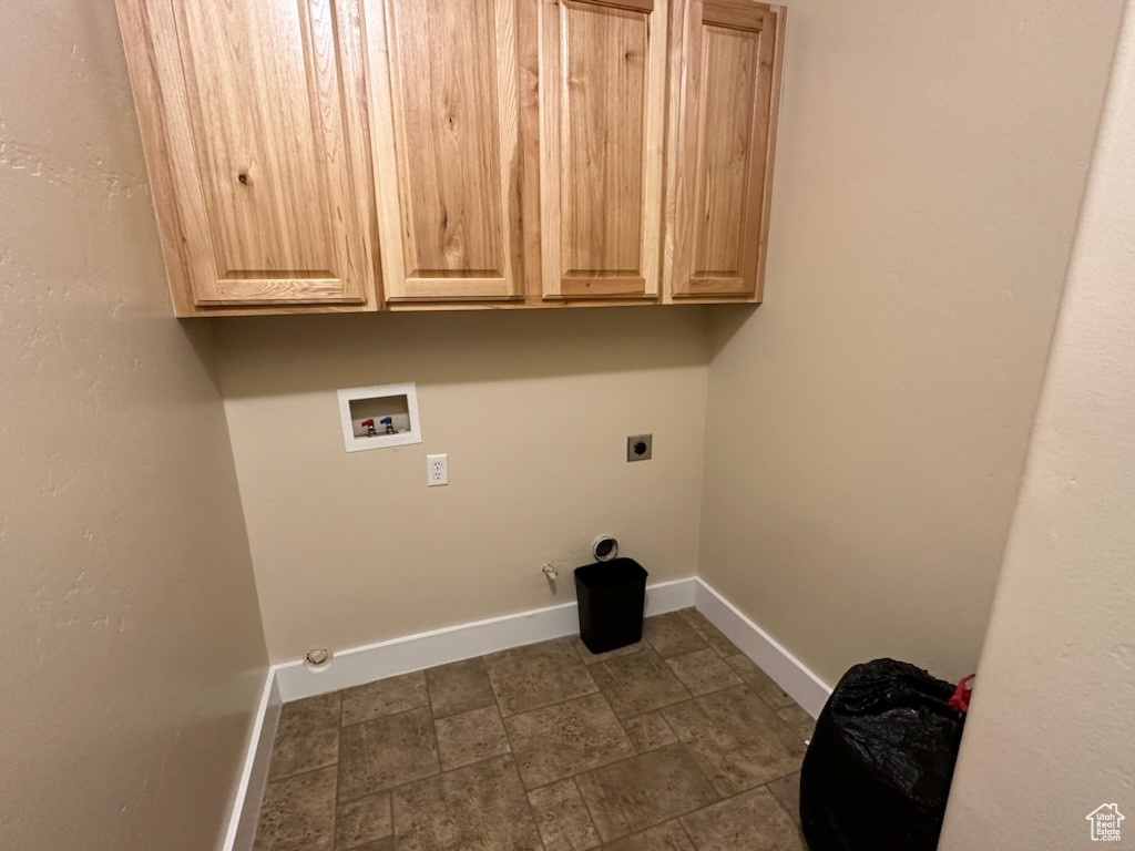 Washroom with dark tile floors, electric dryer hookup, washer hookup, hookup for a gas dryer, and cabinets