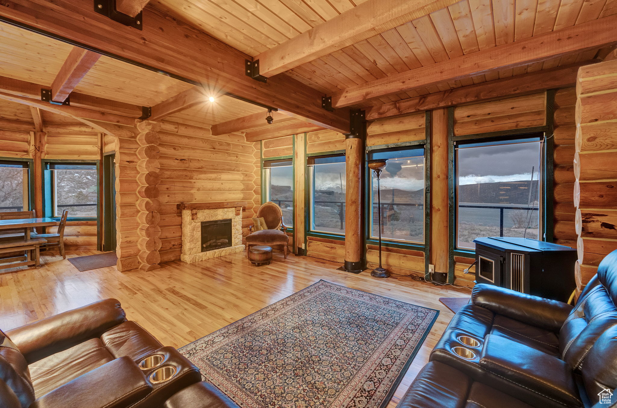 Living room with beamed ceiling, a wealth of natural light, log walls, and light wood-type flooring