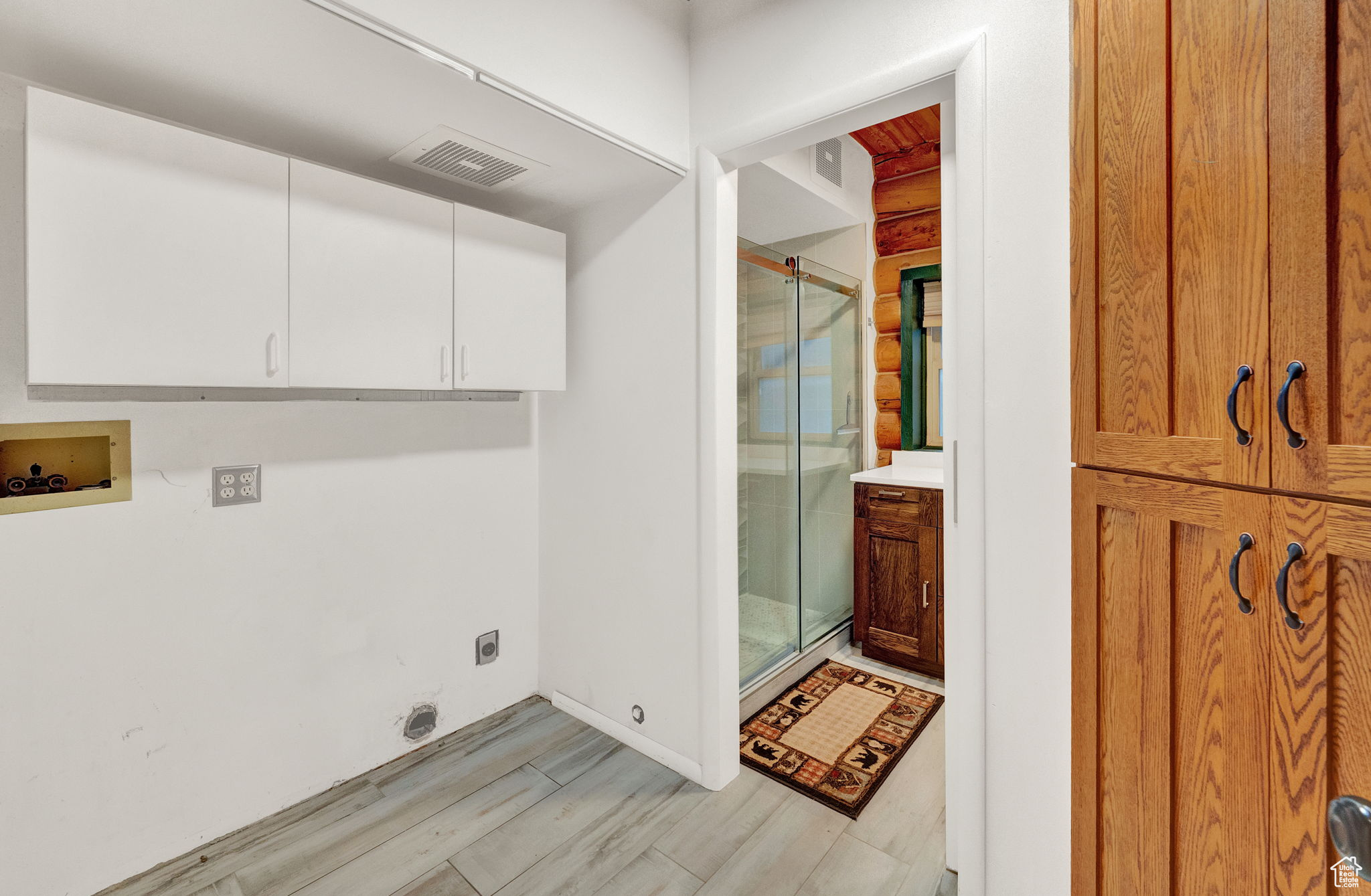 Laundry area with washer hookup, hookup for an electric dryer, cabinets, and light hardwood / wood-style floors