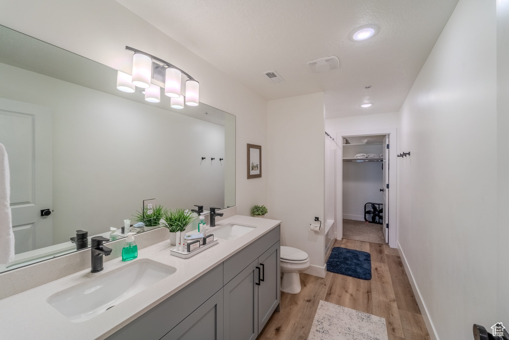 Bathroom with hardwood / wood-style floors, dual bowl vanity, and toilet