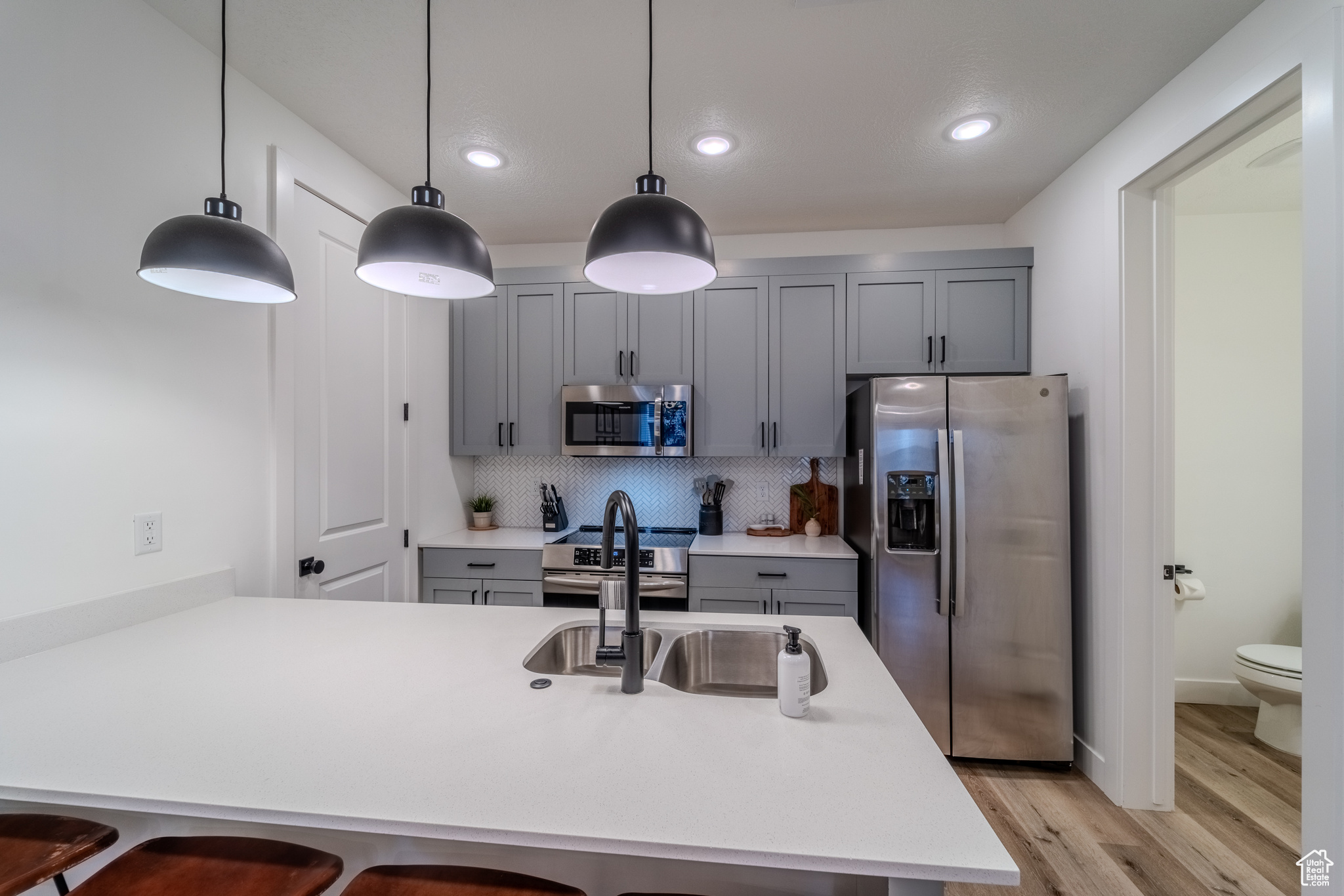 Kitchen featuring decorative light fixtures, light hardwood / wood-style flooring, tasteful backsplash, and stainless steel appliances
