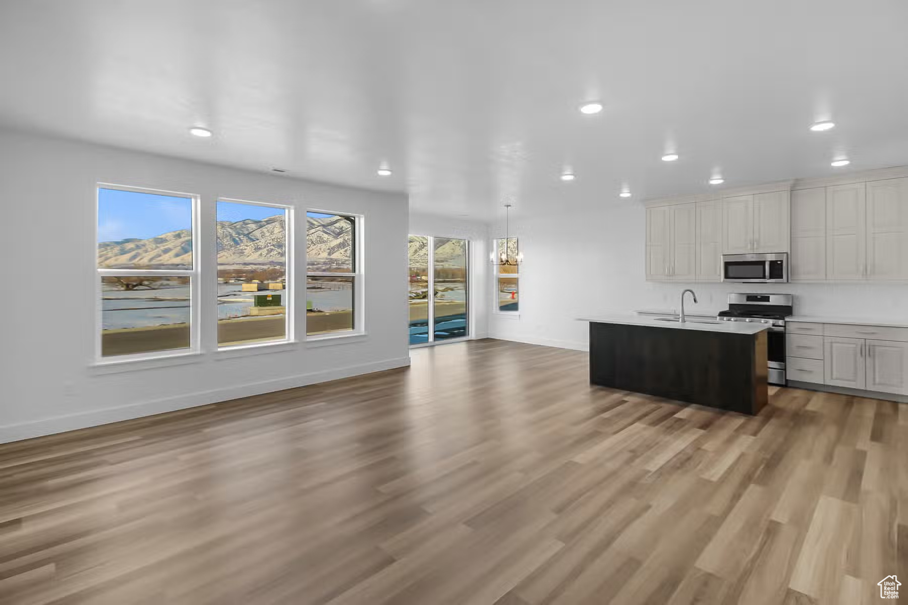 Kitchen with a wealth of natural light, appliances with stainless steel finishes, light hardwood / wood-style floors, and a kitchen island with sink