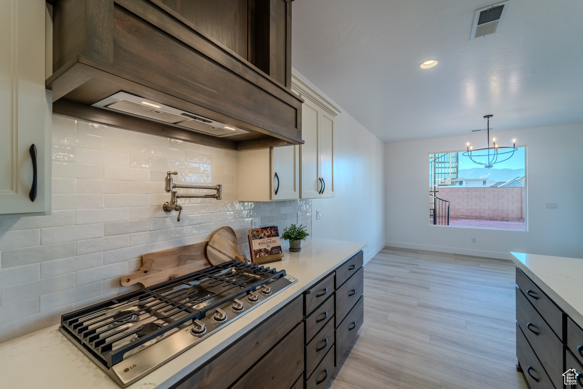 Kitchen with white cabinetry, tasteful backsplash, light hardwood / wood-style flooring, and pendant lighting