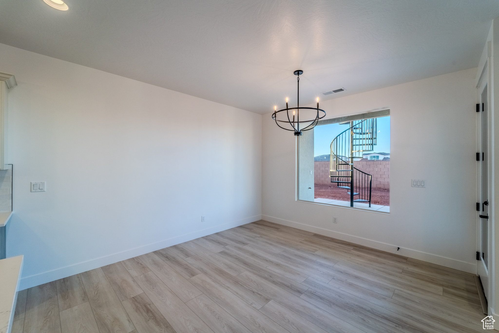 Empty room featuring light hardwood / wood-style flooring and a notable chandelier