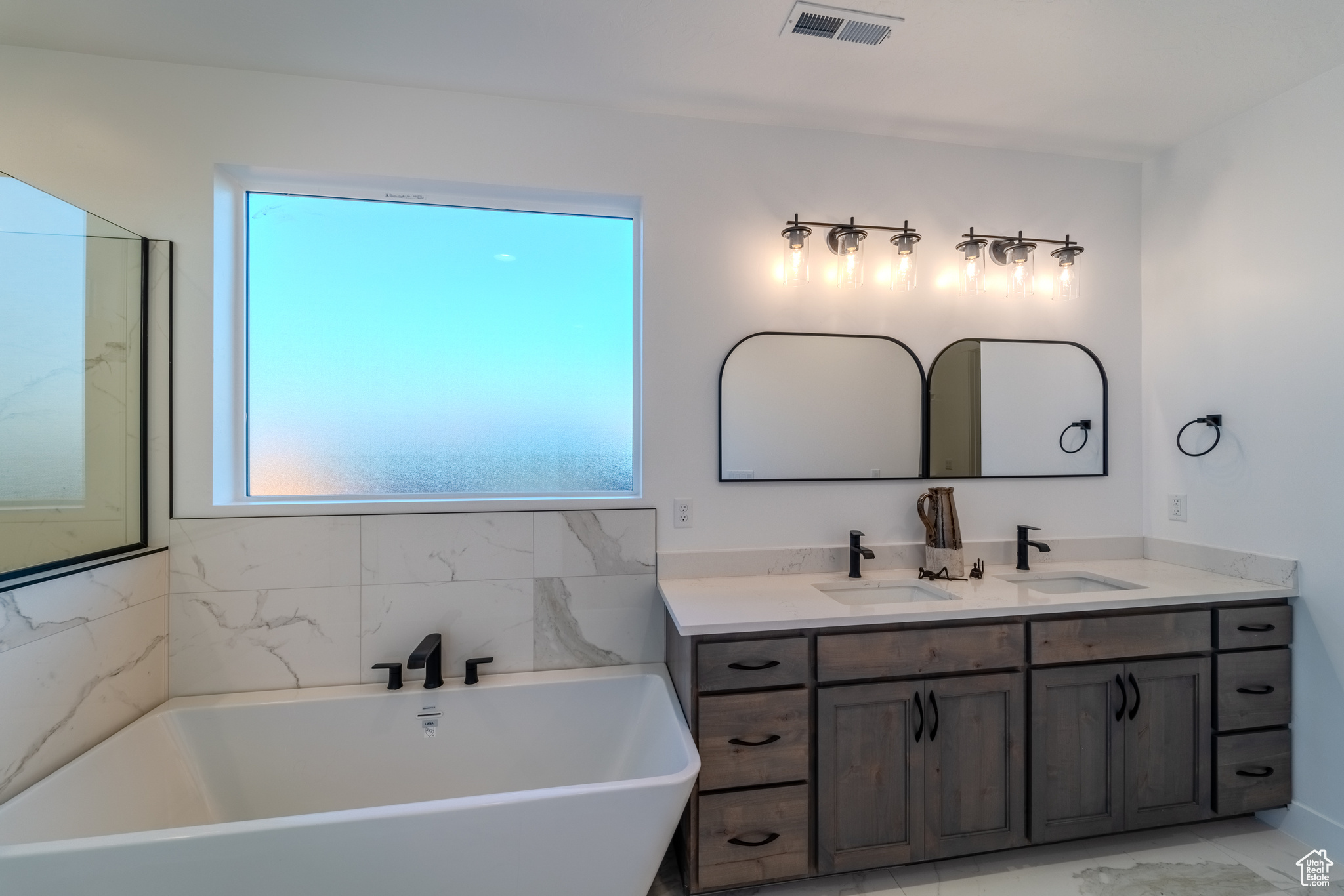 Bathroom with tile patterned flooring, a tub, and vanity