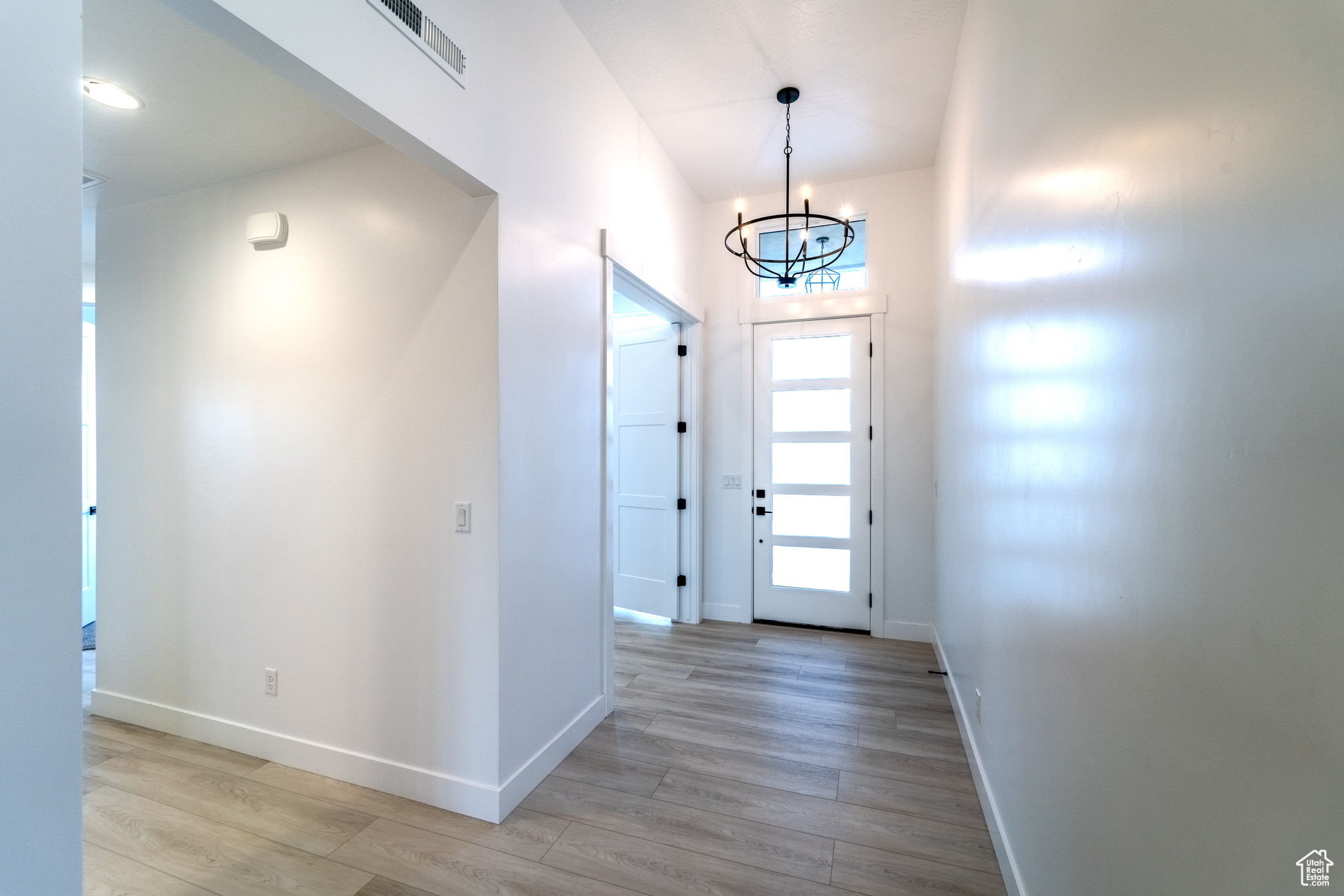 Entrance foyer featuring light hardwood / wood-style flooring and an inviting chandelier