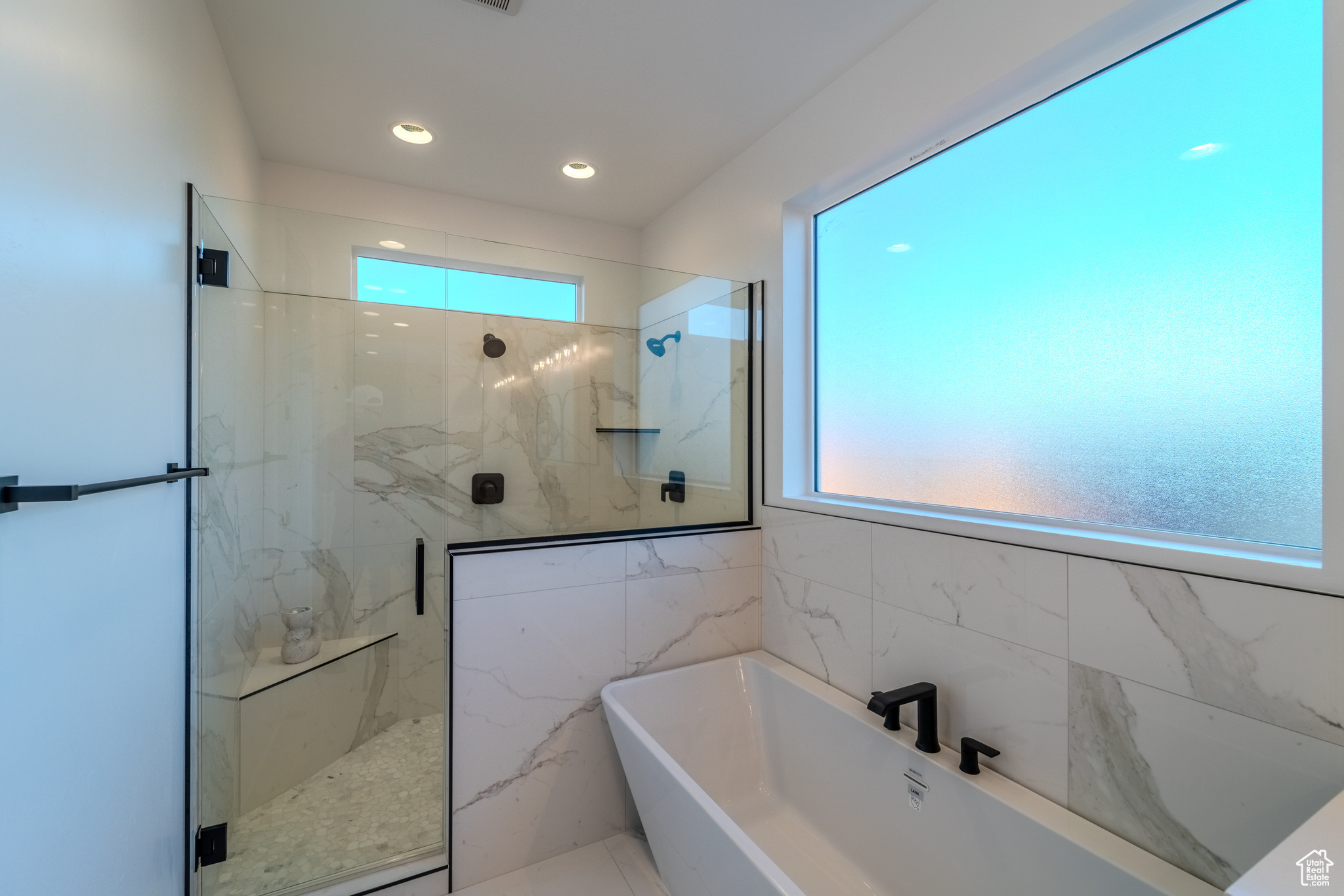 Bathroom featuring tile walls and independent shower and bath