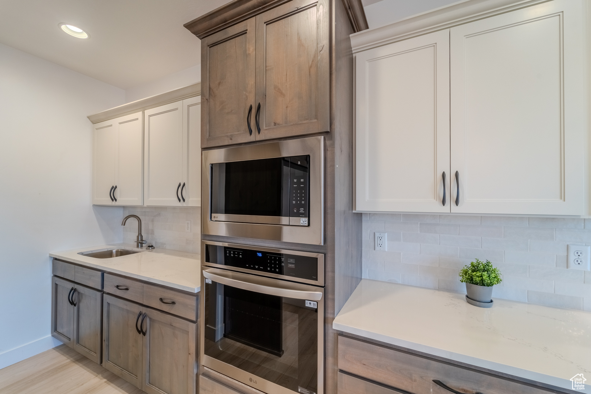 Kitchen with appliances with stainless steel finishes, sink, backsplash, and white cabinets