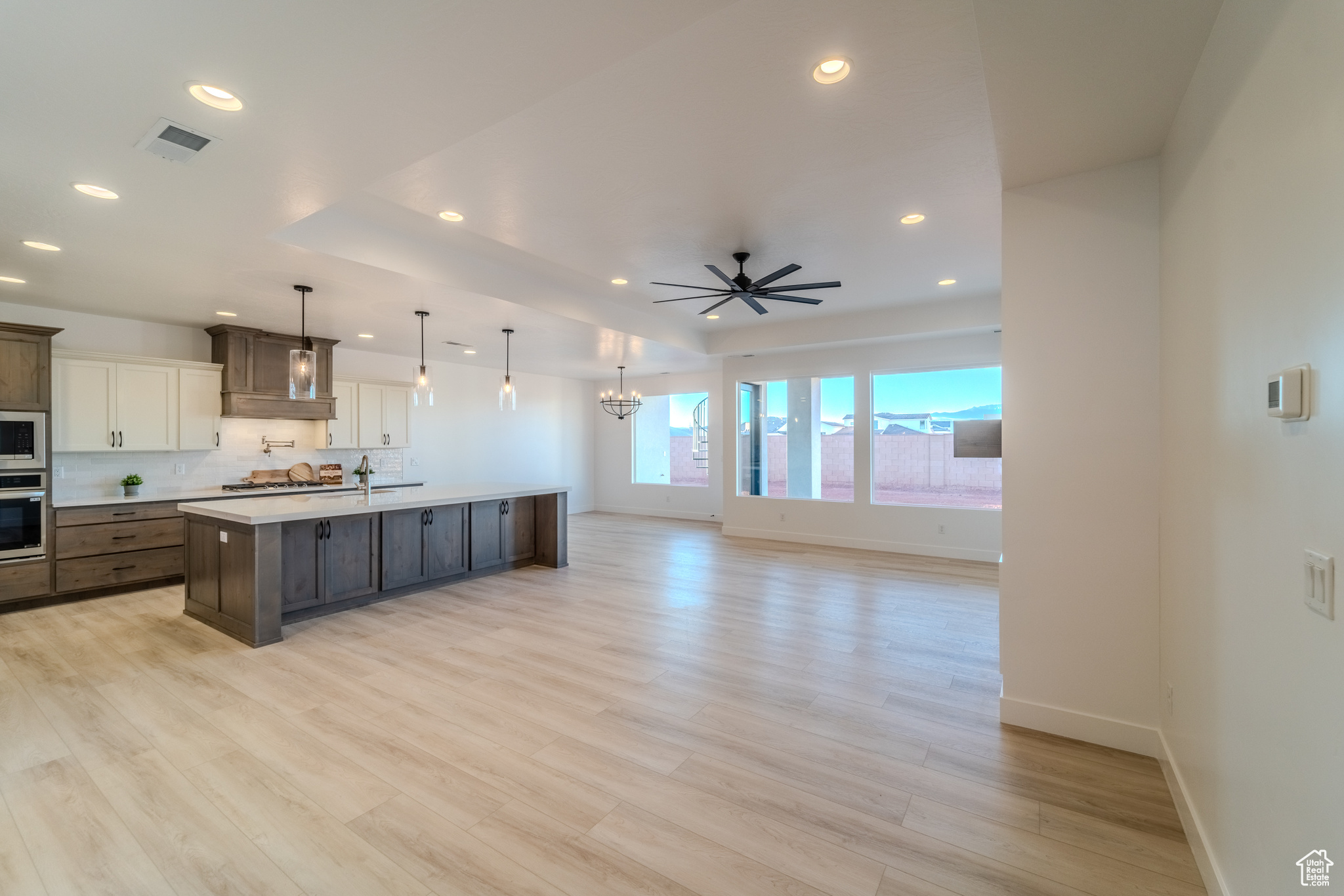 Kitchen featuring light hardwood / wood-style flooring, decorative light fixtures, oven, an island with sink, and built in microwave