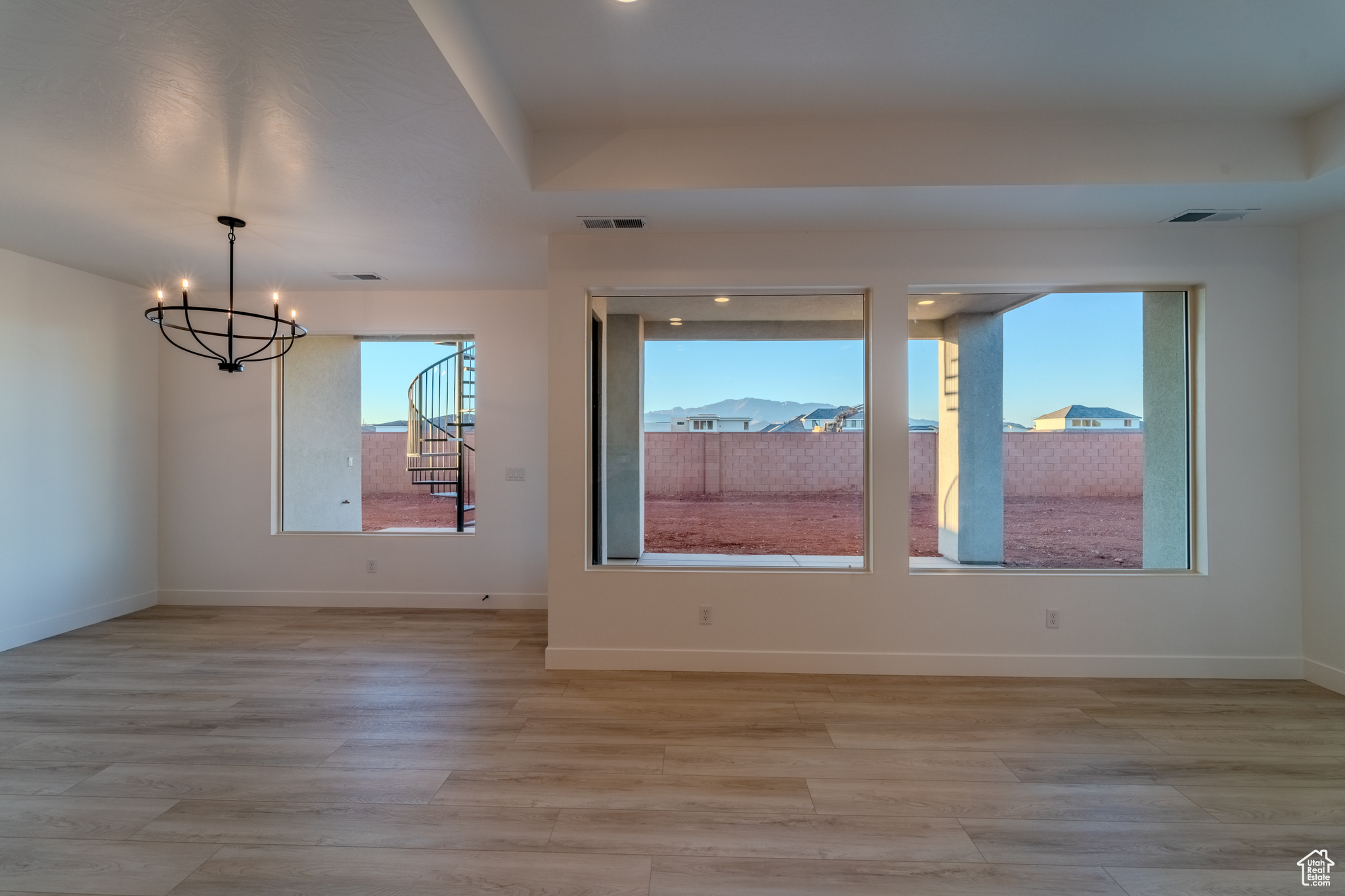 Empty room with an inviting chandelier and light wood-type flooring