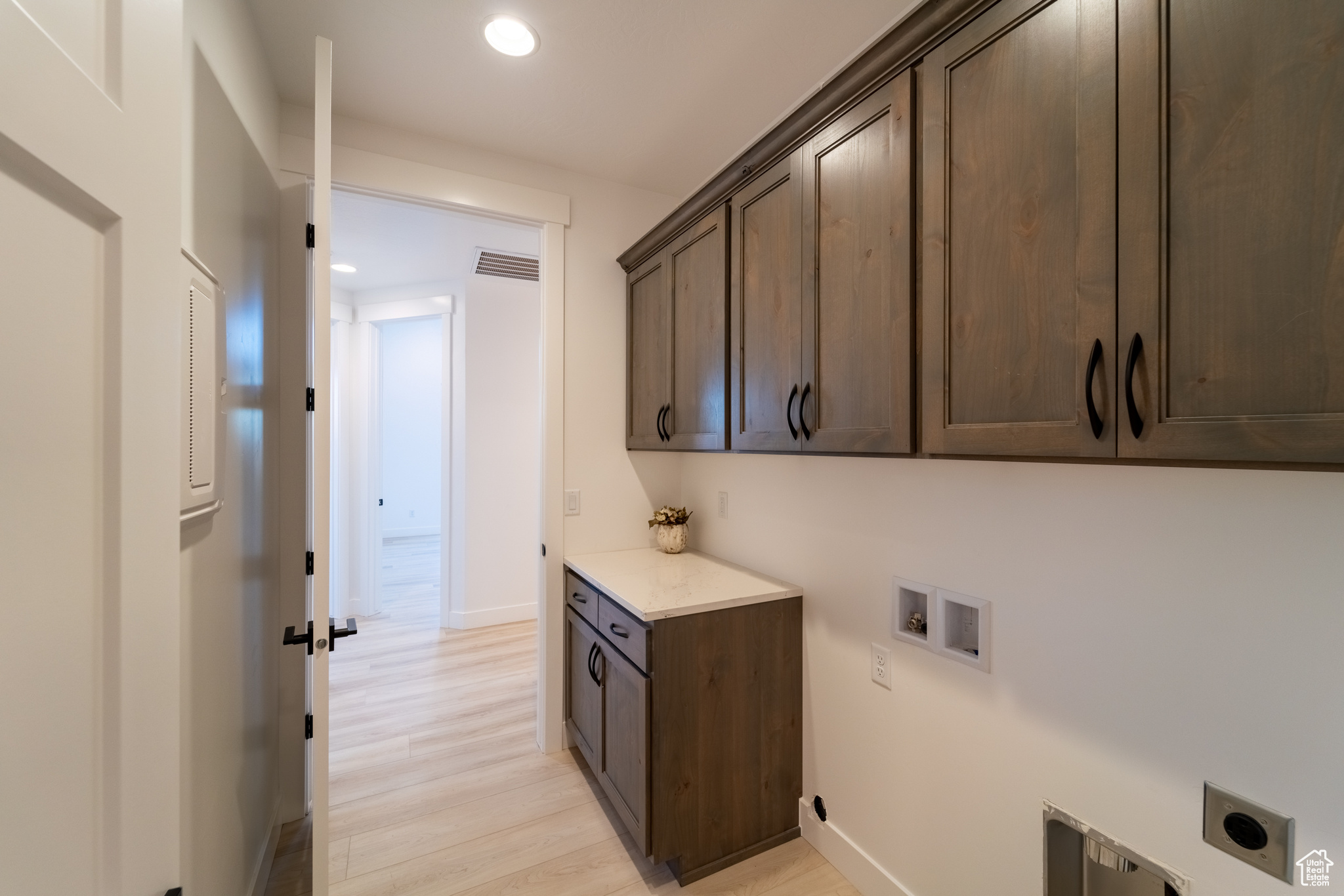 Washroom with washer hookup, electric dryer hookup, cabinets, and light wood-type flooring