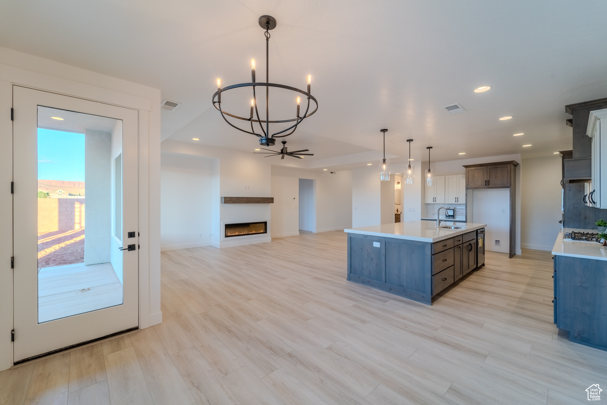 Kitchen featuring sink, light hardwood / wood-style floors, an island with sink, and hanging light fixtures