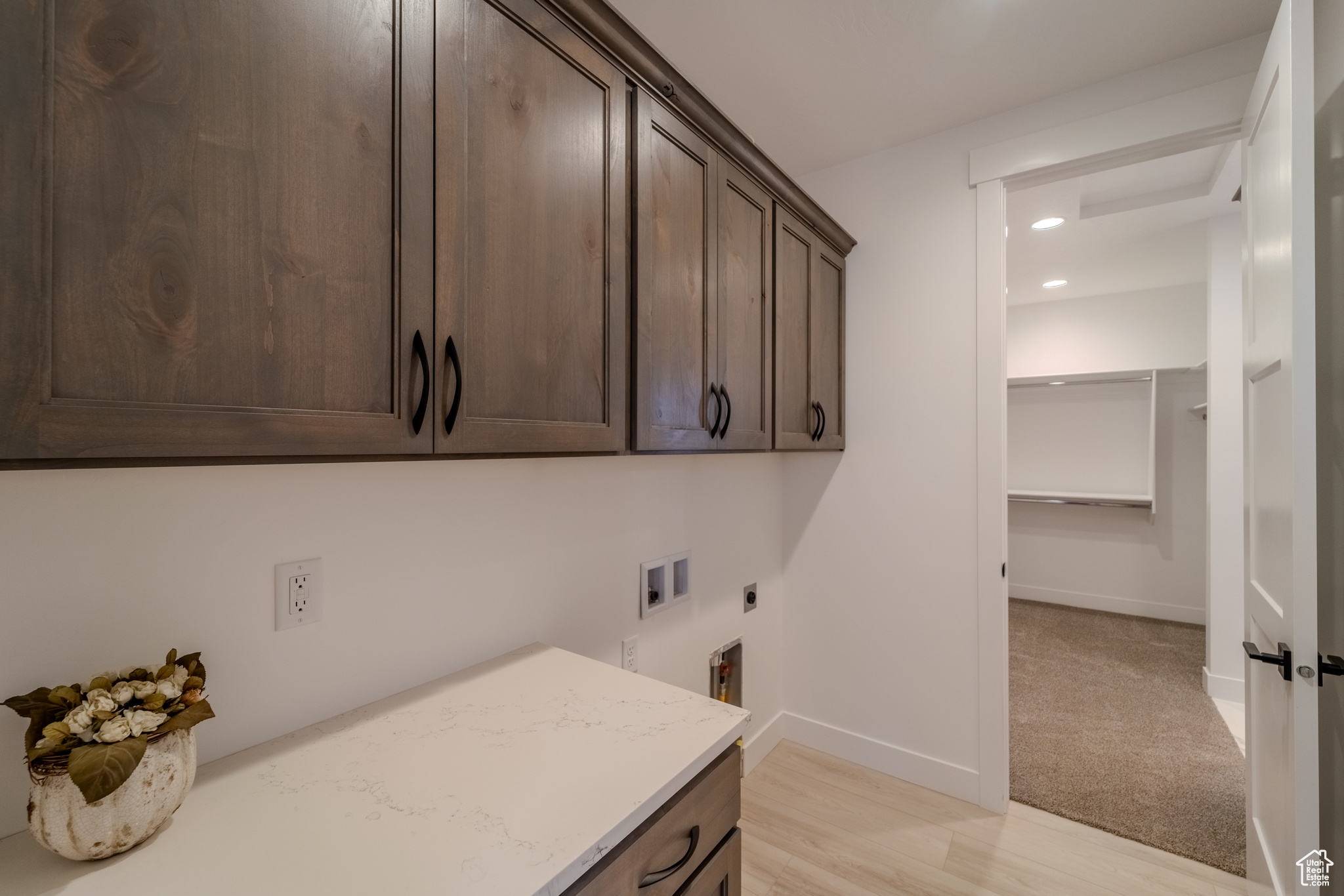 Laundry area with hookup for an electric dryer, light hardwood / wood-style flooring, washer hookup, and cabinets