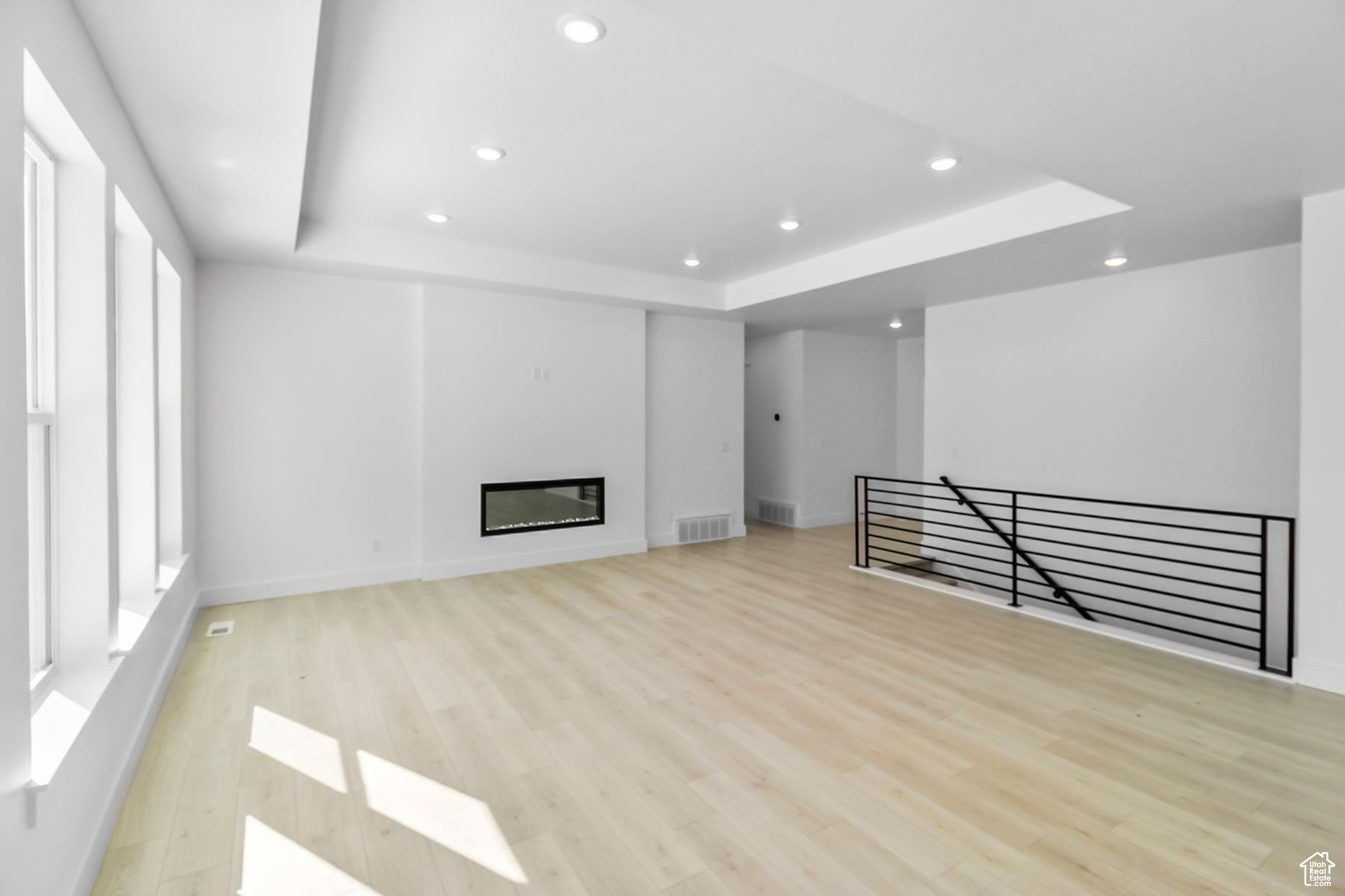 Unfurnished living room featuring a raised ceiling and light hardwood / wood-style floors