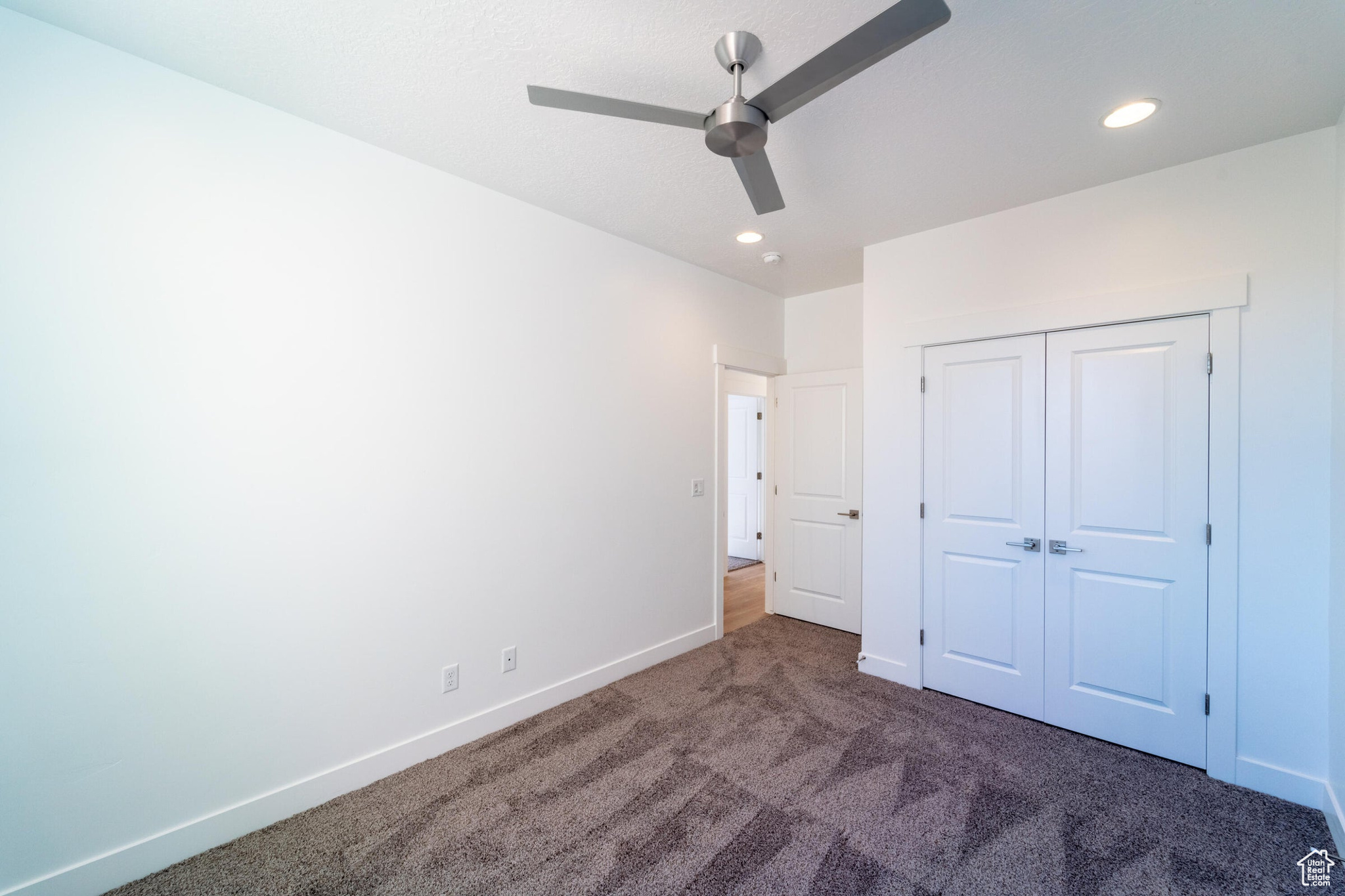 Unfurnished bedroom with a closet, ceiling fan, and dark carpet