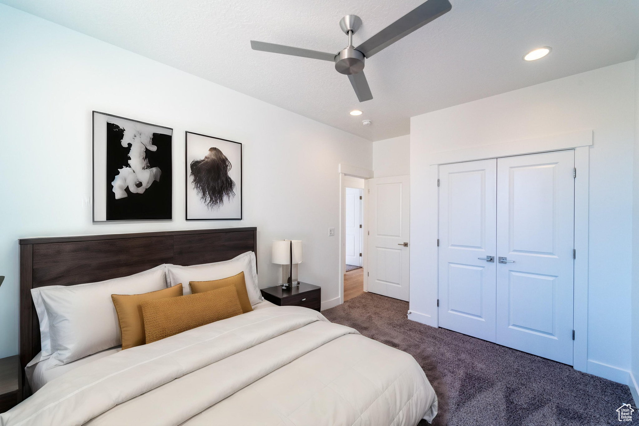 Bedroom with a closet, dark colored carpet, and ceiling fan