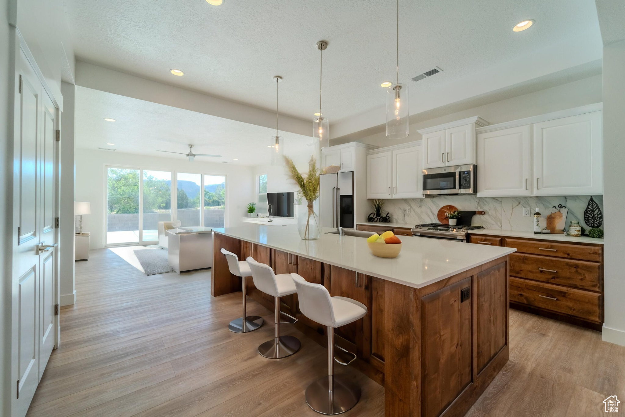 Kitchen featuring stainless steel appliances, decorative backsplash, white cabinets, a center island, and light hardwood / wood-style flooring