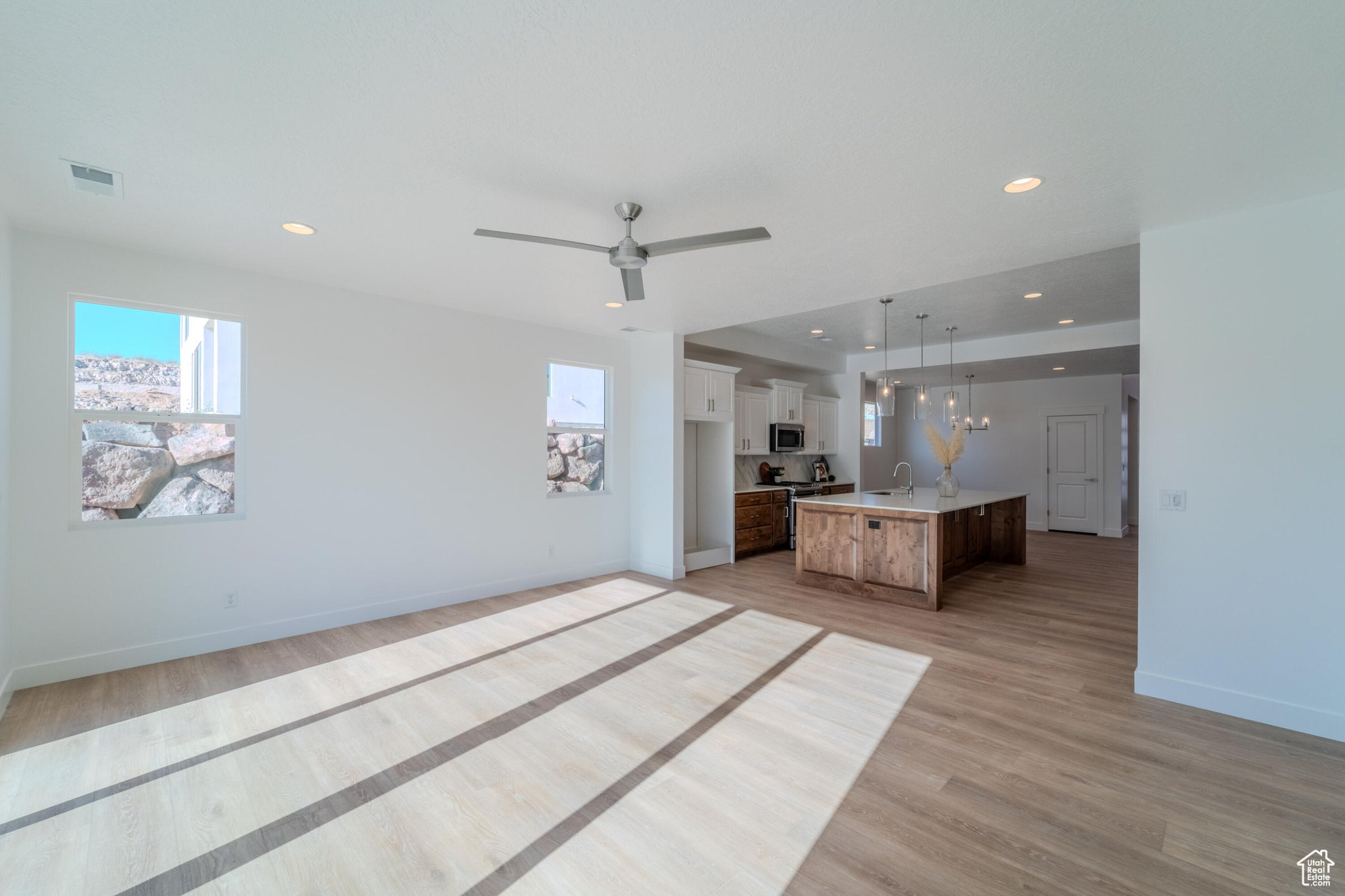 Unfurnished living room with sink, light wood-type flooring, and ceiling fan