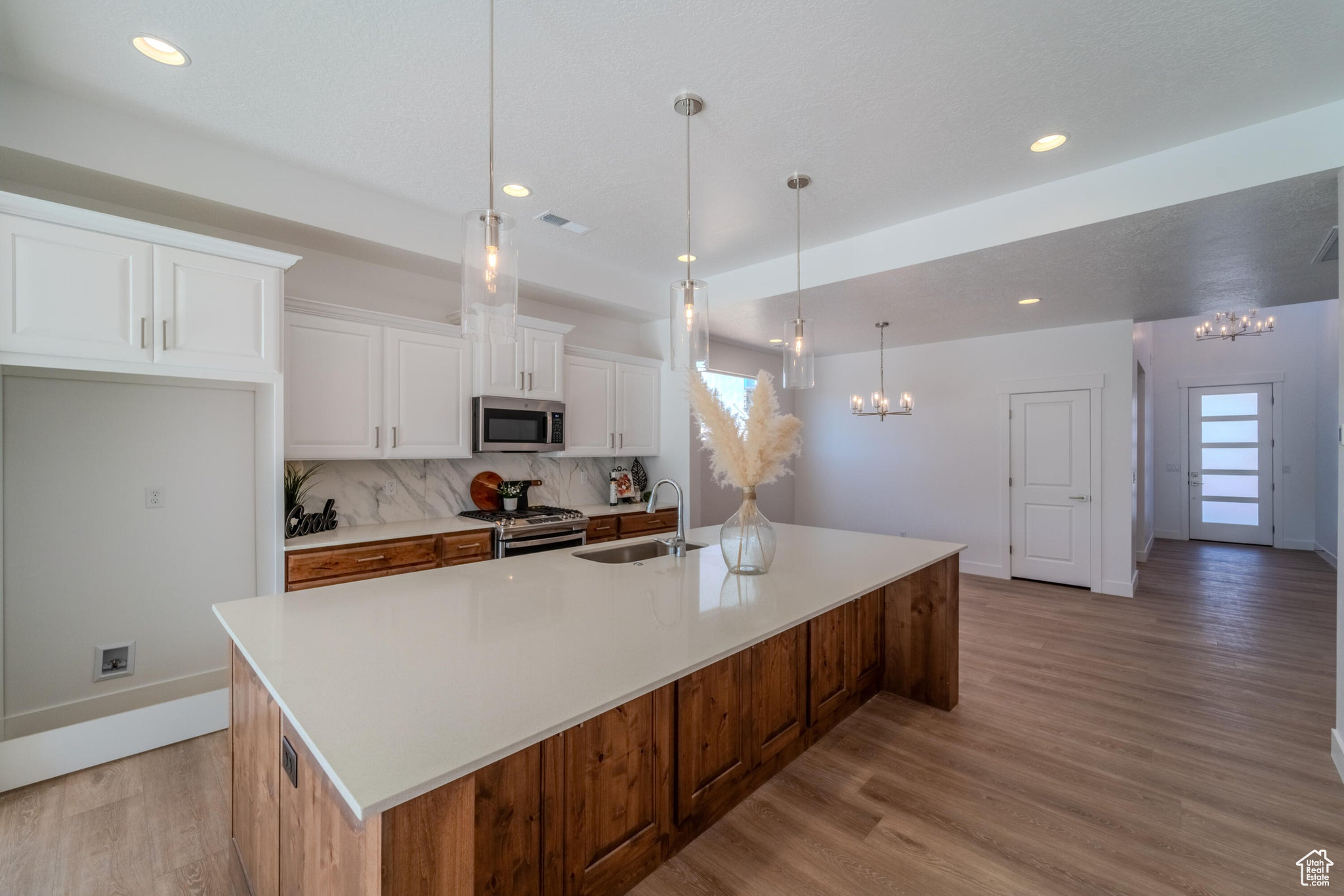 Kitchen with light hardwood / wood-style floors, a large island, backsplash, and stainless steel appliances