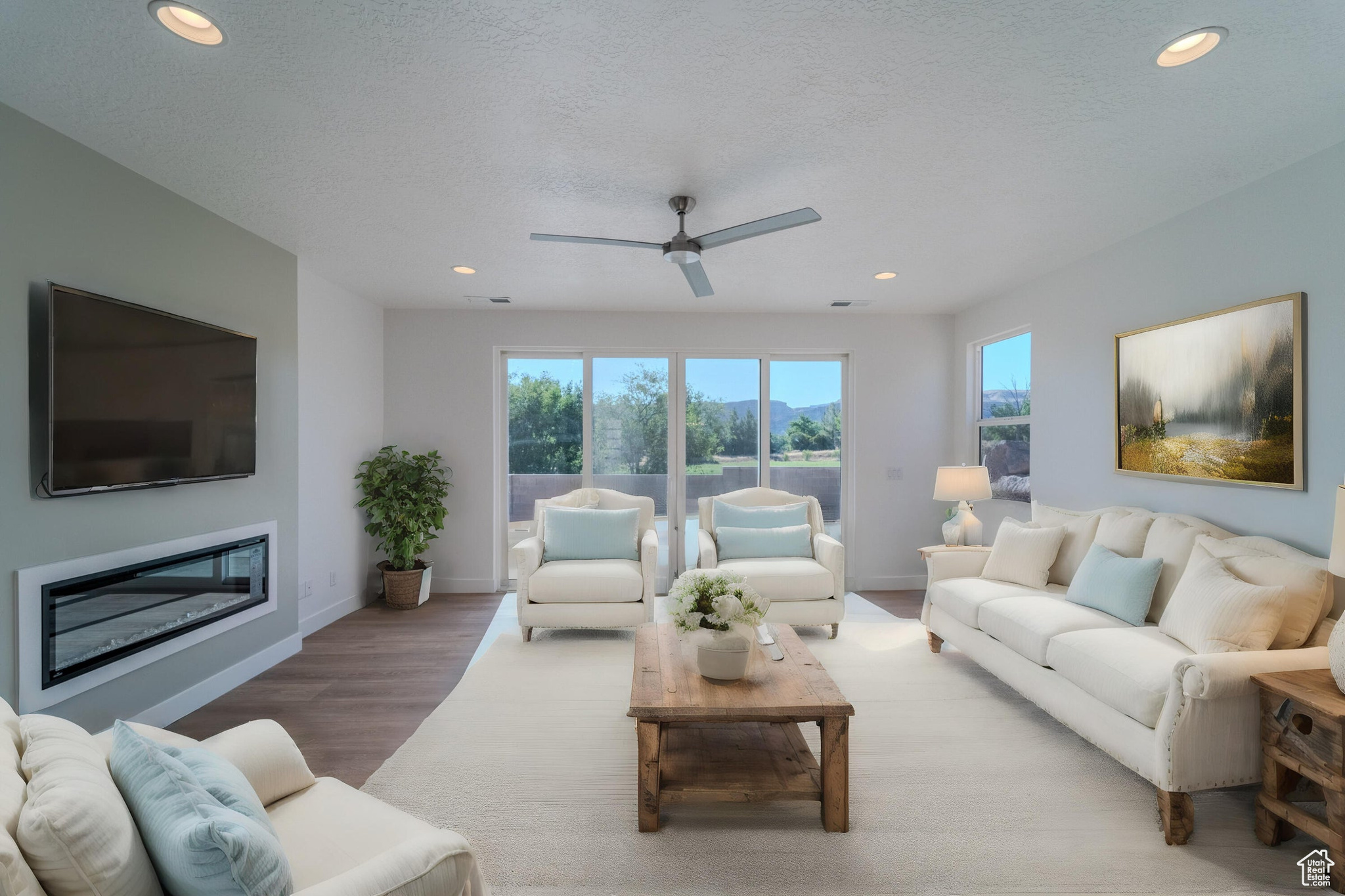 Living room with a textured ceiling, ceiling fan, and hardwood / wood-style floors