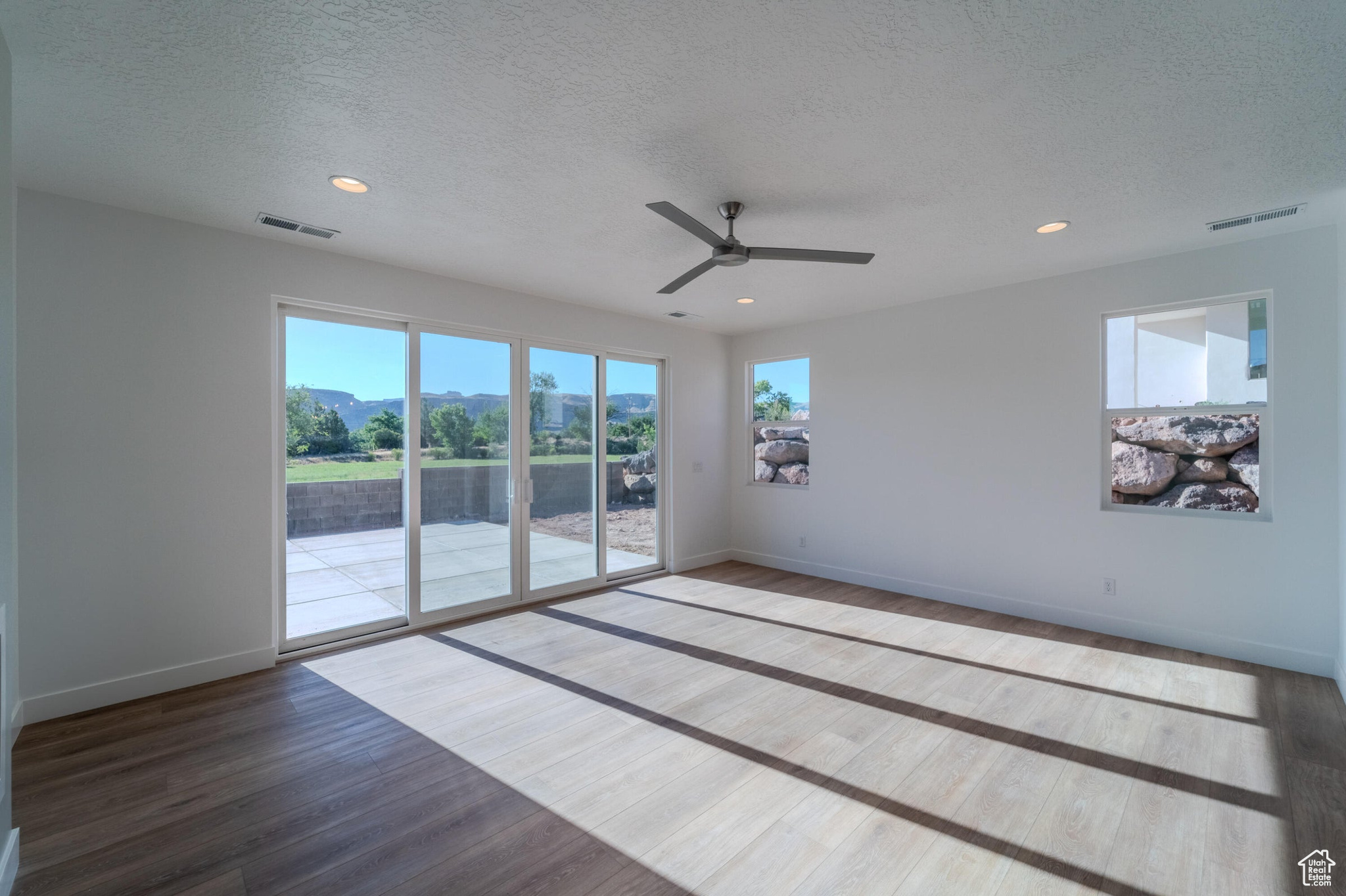 Empty room featuring wood-type flooring, a textured ceiling, and ceiling fan