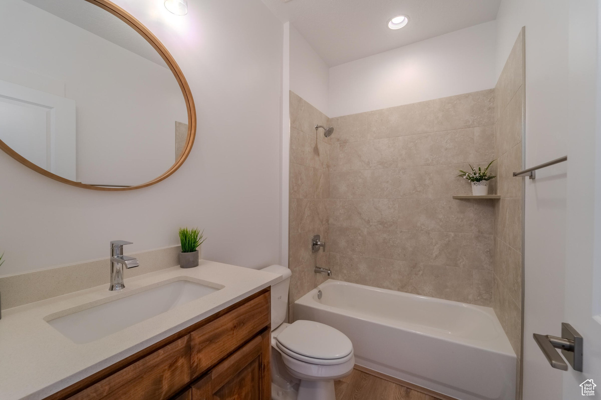 Full bathroom with wood-type flooring, toilet, tiled shower / bath combo, and vanity