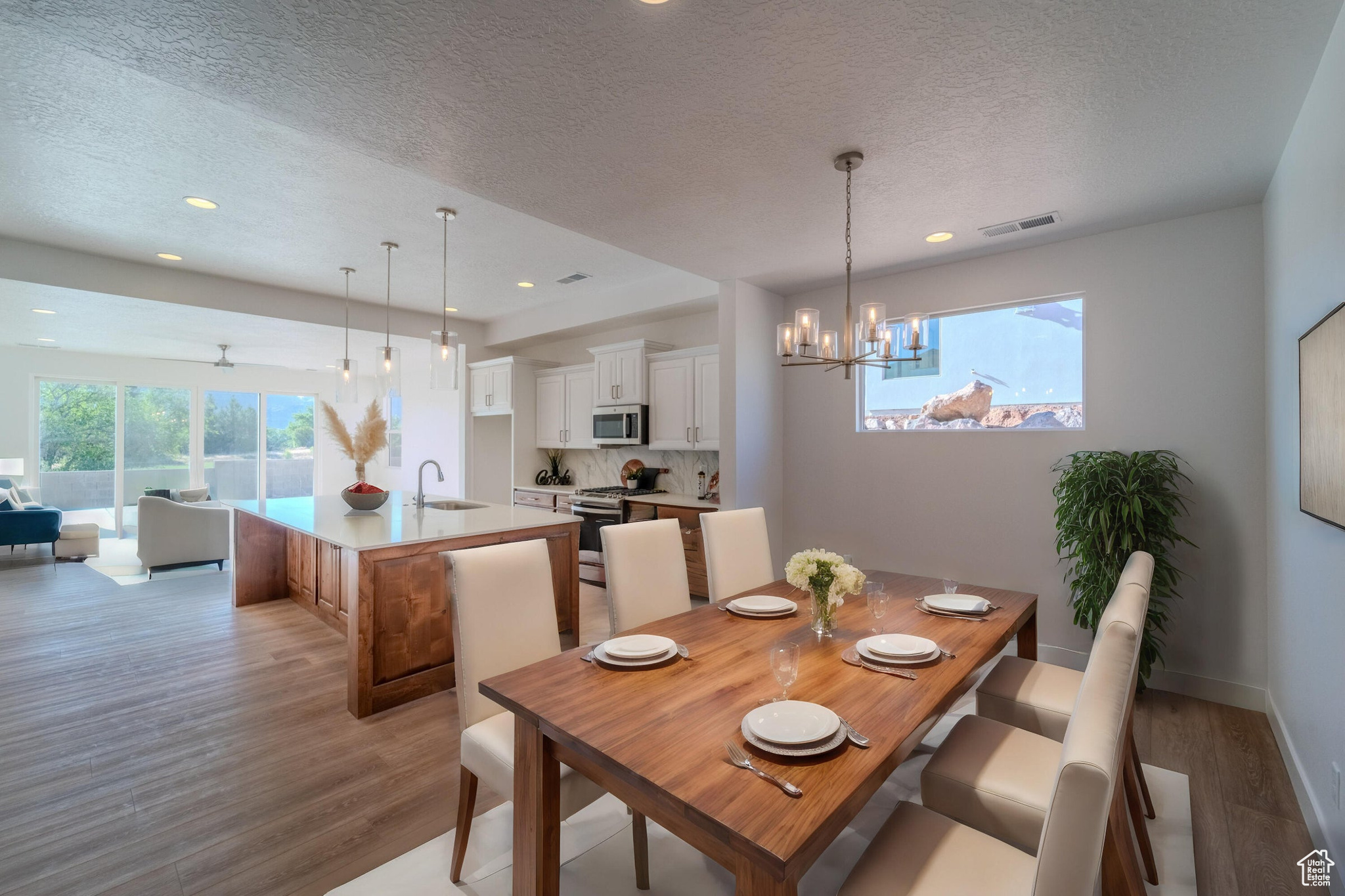 Dining area featuring sink, a textured ceiling, a chandelier, and light hardwood / wood-style floors