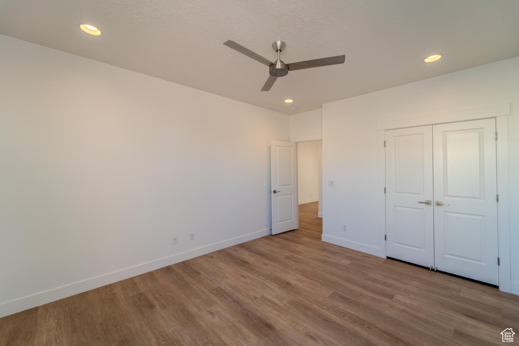 Unfurnished bedroom with ceiling fan, hardwood / wood-style floors, and a closet