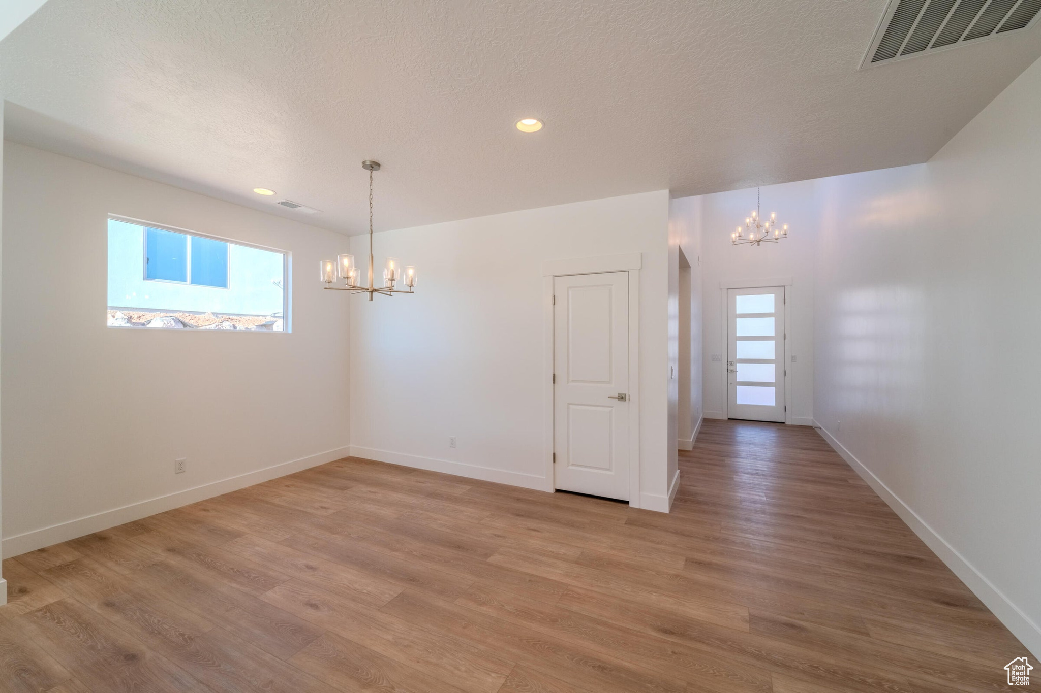 Unfurnished room with an inviting chandelier, a textured ceiling, and hardwood / wood-style flooring