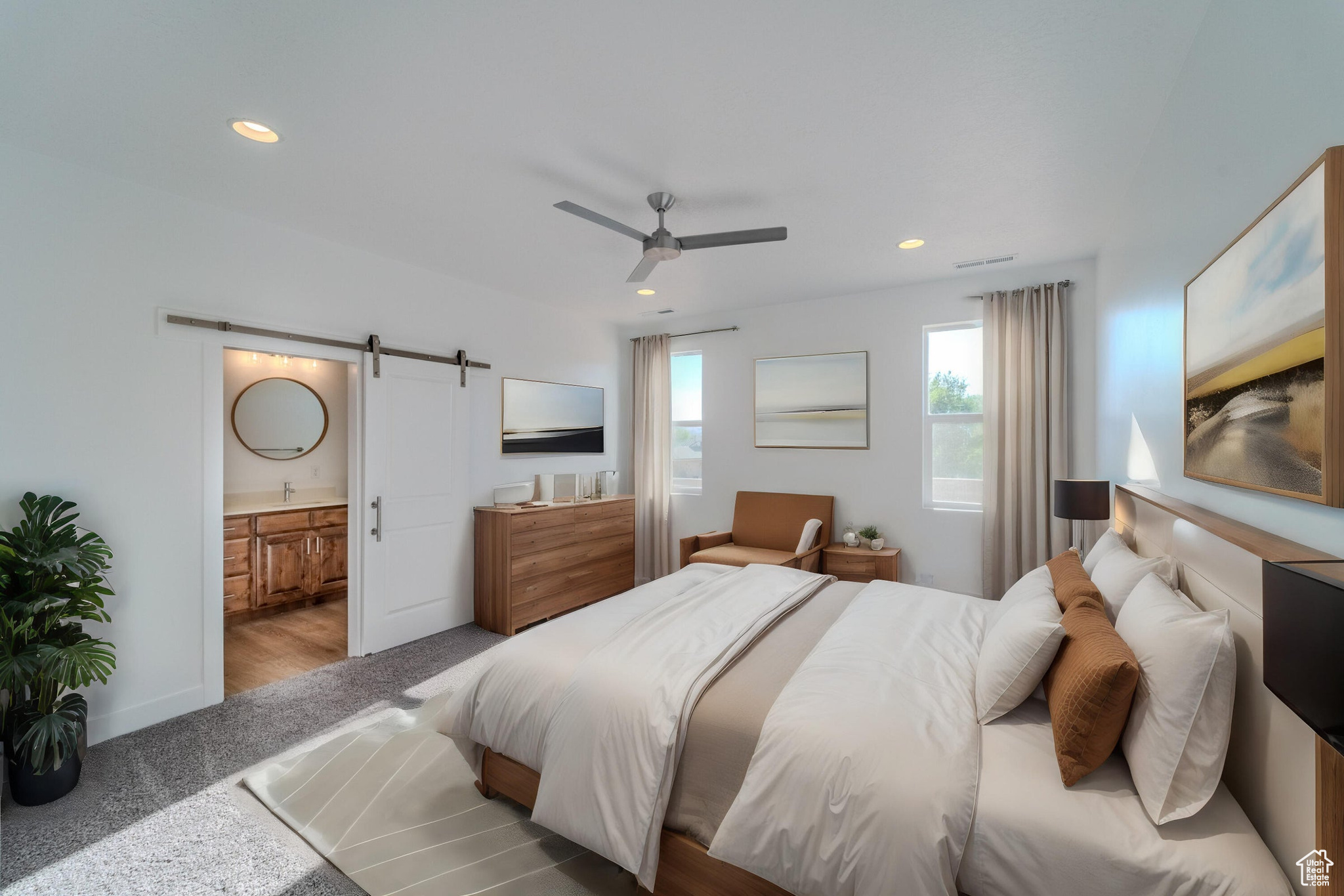 Carpeted bedroom with ceiling fan, connected bathroom, and a barn door