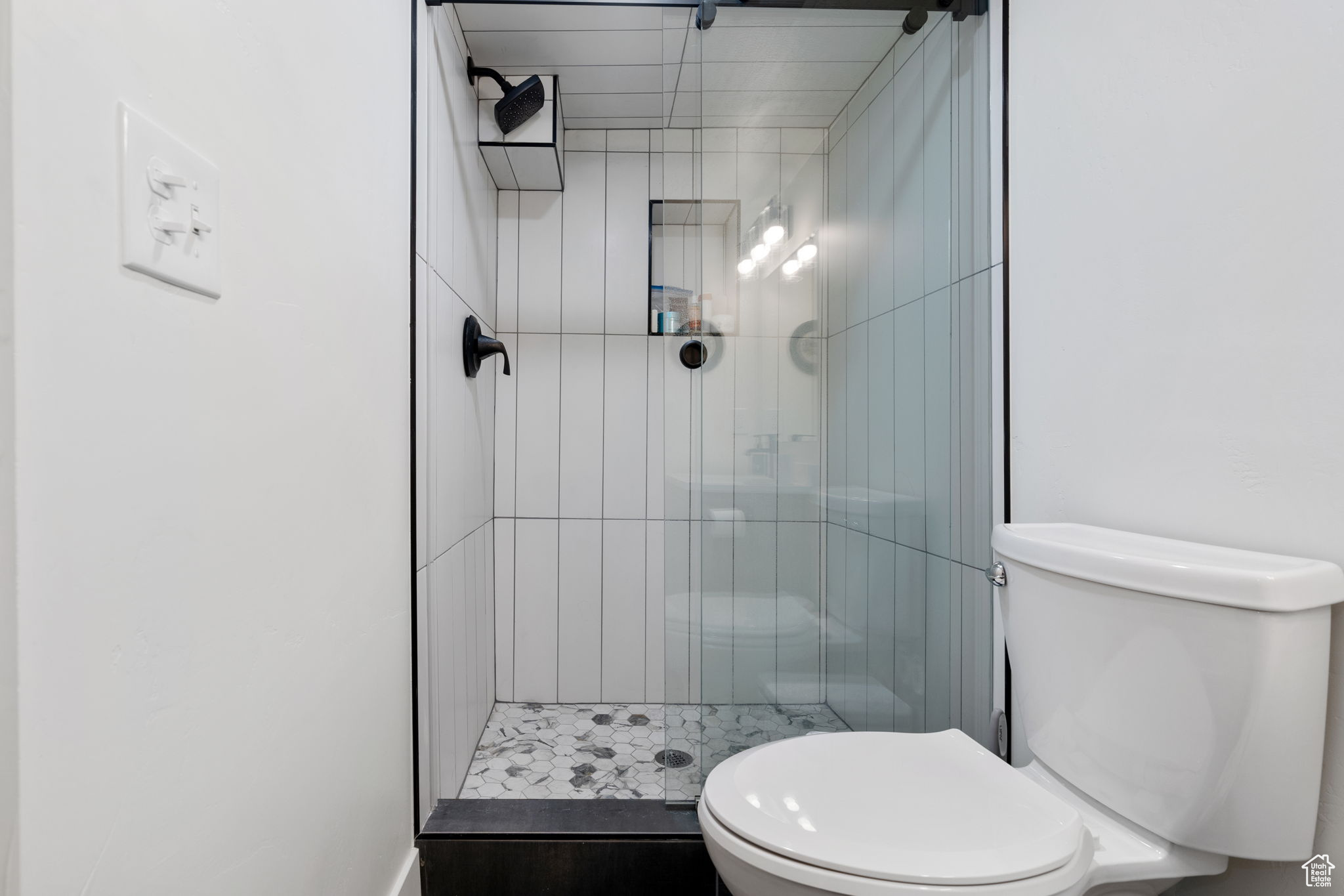 Bathroom featuring tiled shower and toilet
