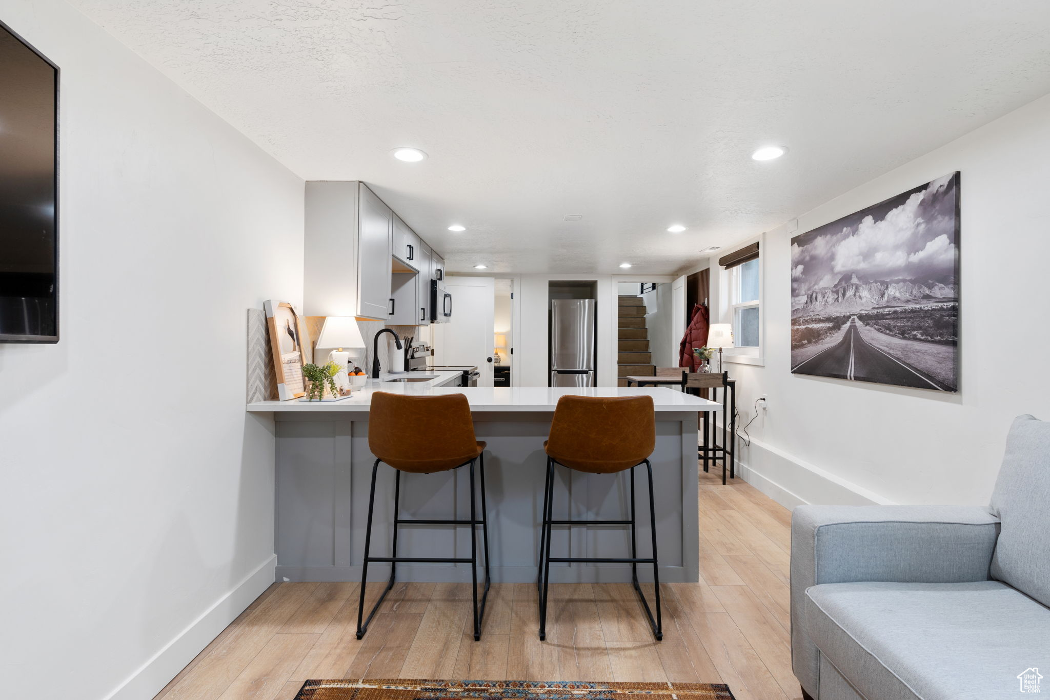 Kitchen featuring a kitchen breakfast bar, kitchen peninsula, light wood-type flooring, and stainless steel fridge
