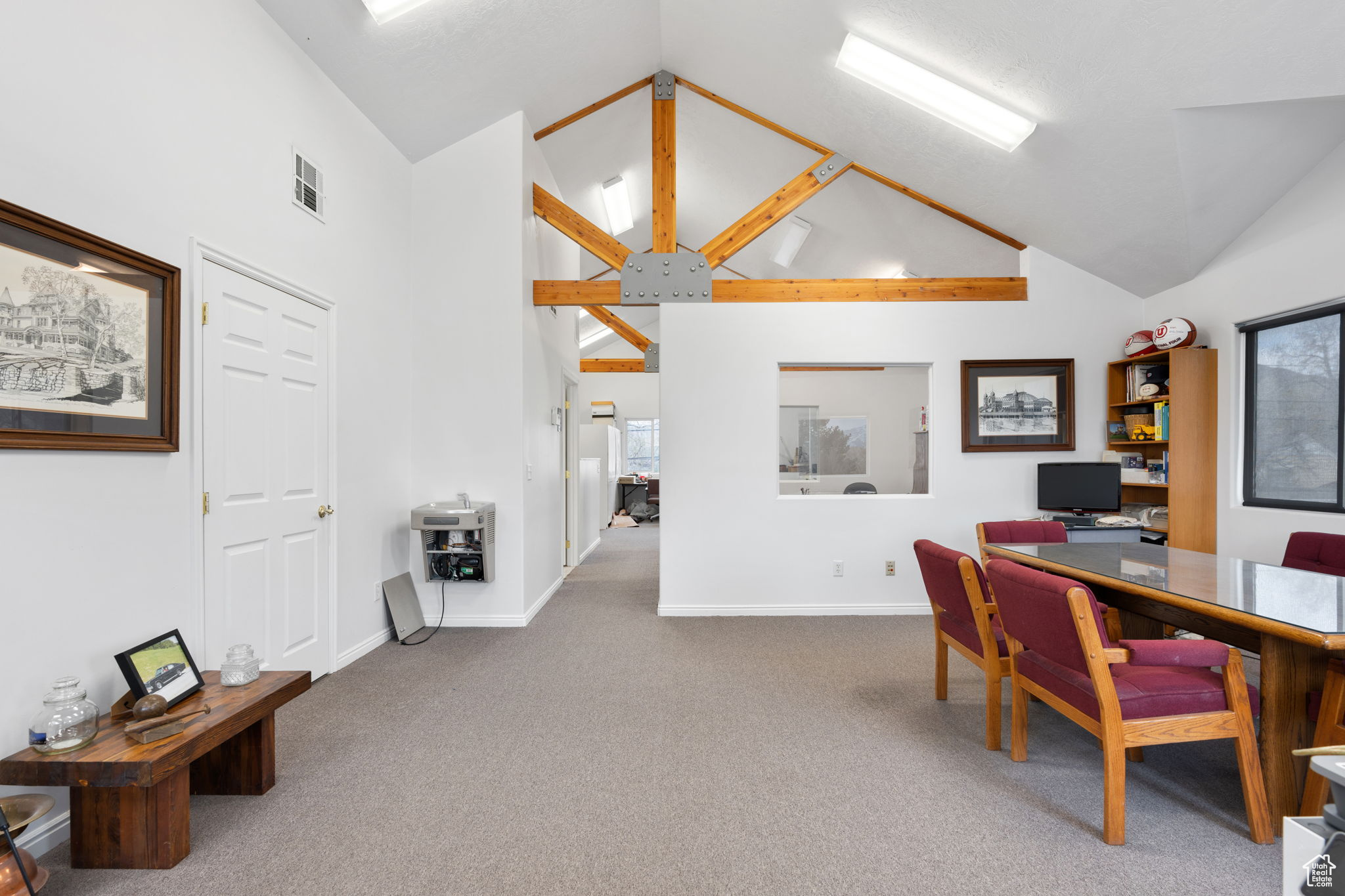 Carpeted office space with high vaulted ceiling and beamed ceiling