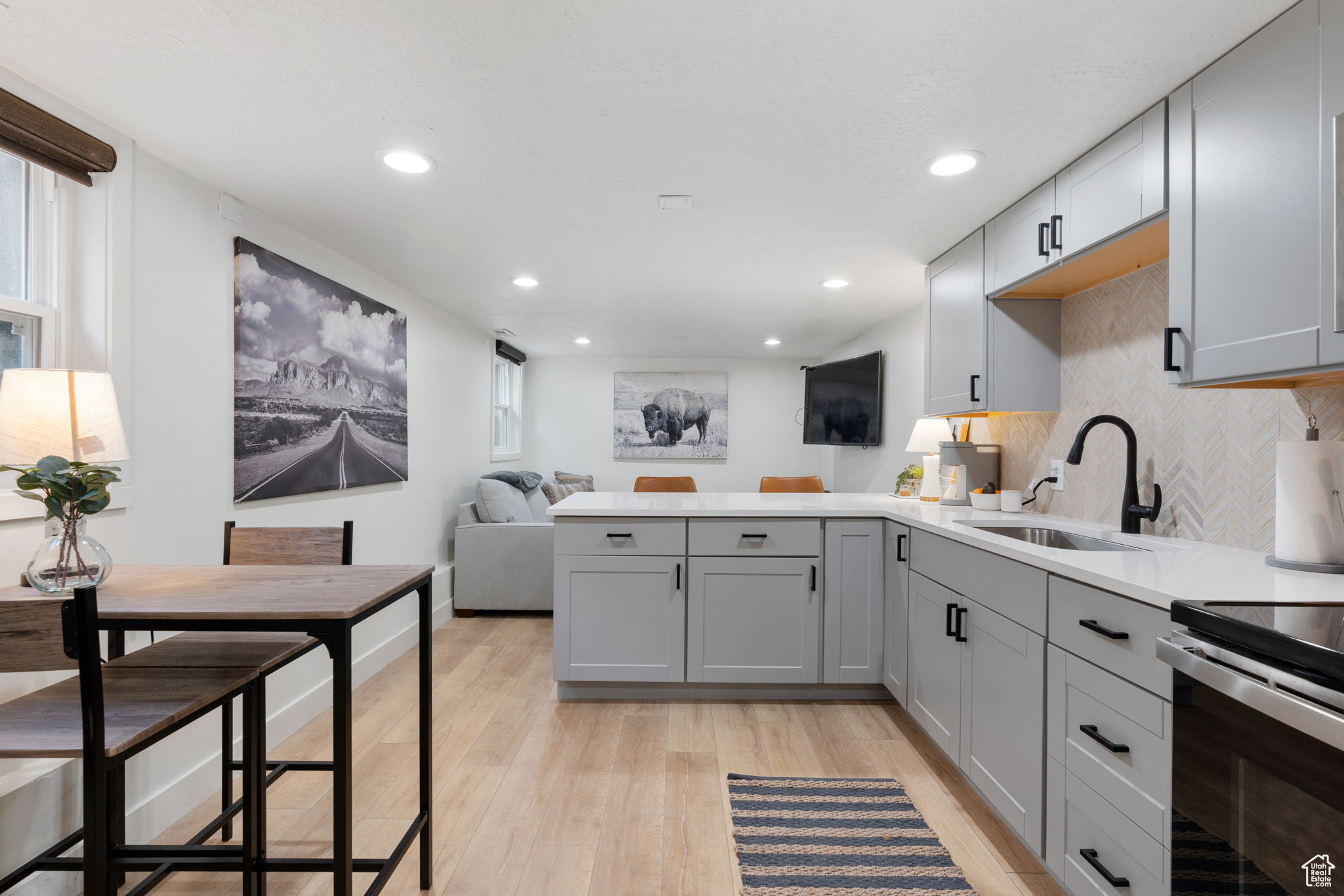 Kitchen featuring kitchen peninsula, light hardwood / wood-style flooring, gray cabinets, tasteful backsplash, and sink