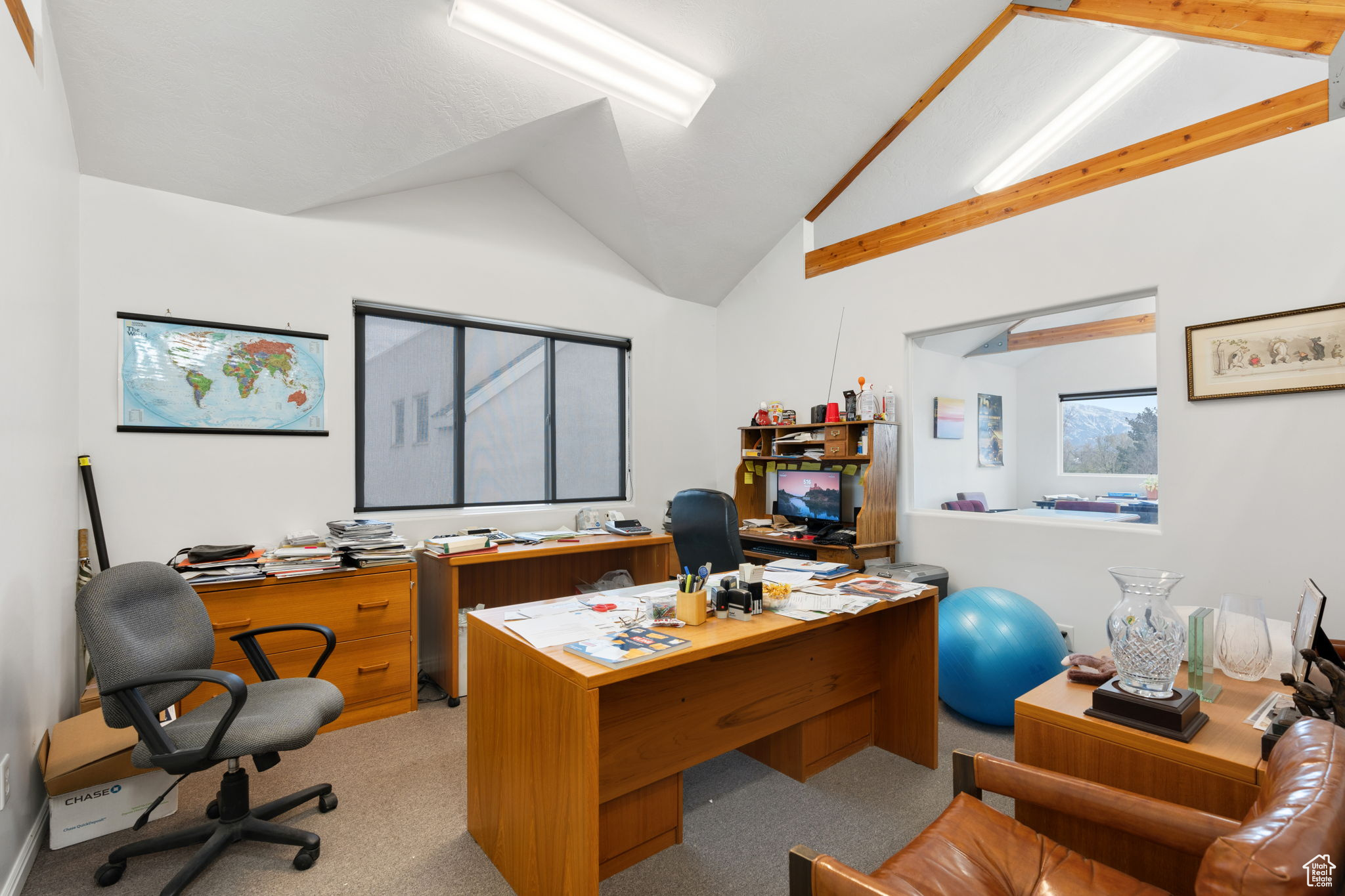 Carpeted office space with lofted ceiling with beams