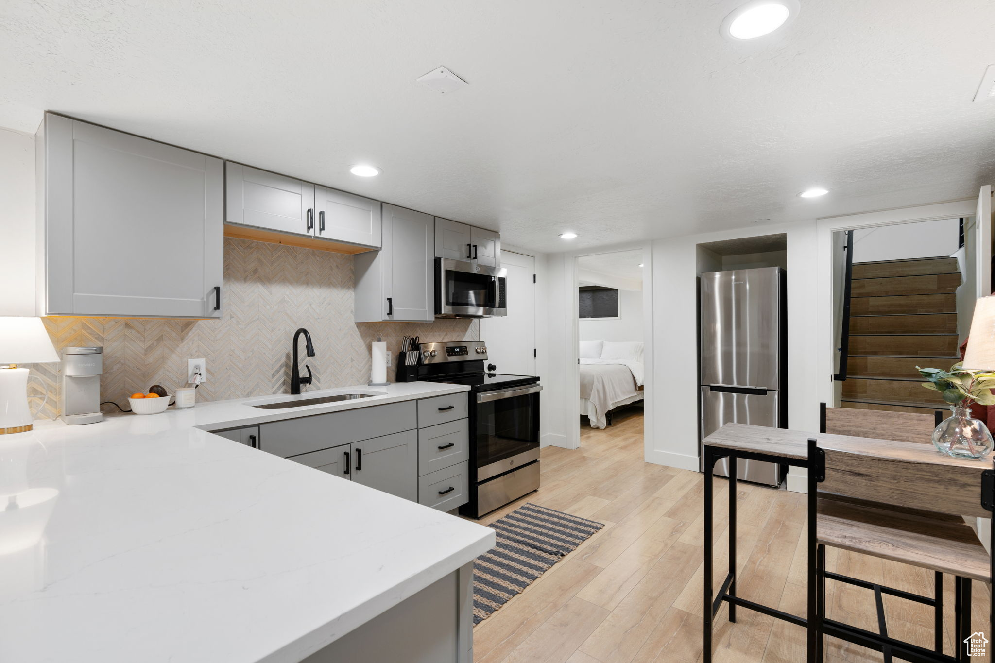 Kitchen featuring gray cabinetry, appliances with stainless steel finishes, sink, and light wood-type flooring