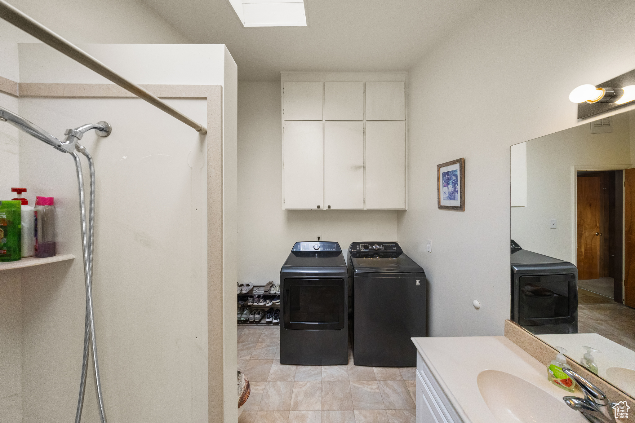 Laundry area featuring sink, independent washer and dryer, and light tile flooring