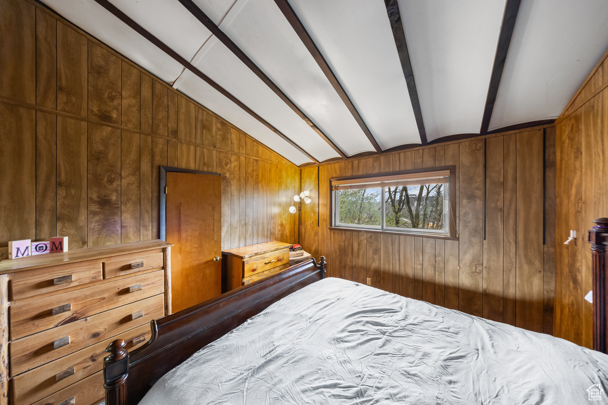 Bedroom with wood walls and vaulted ceiling with beams