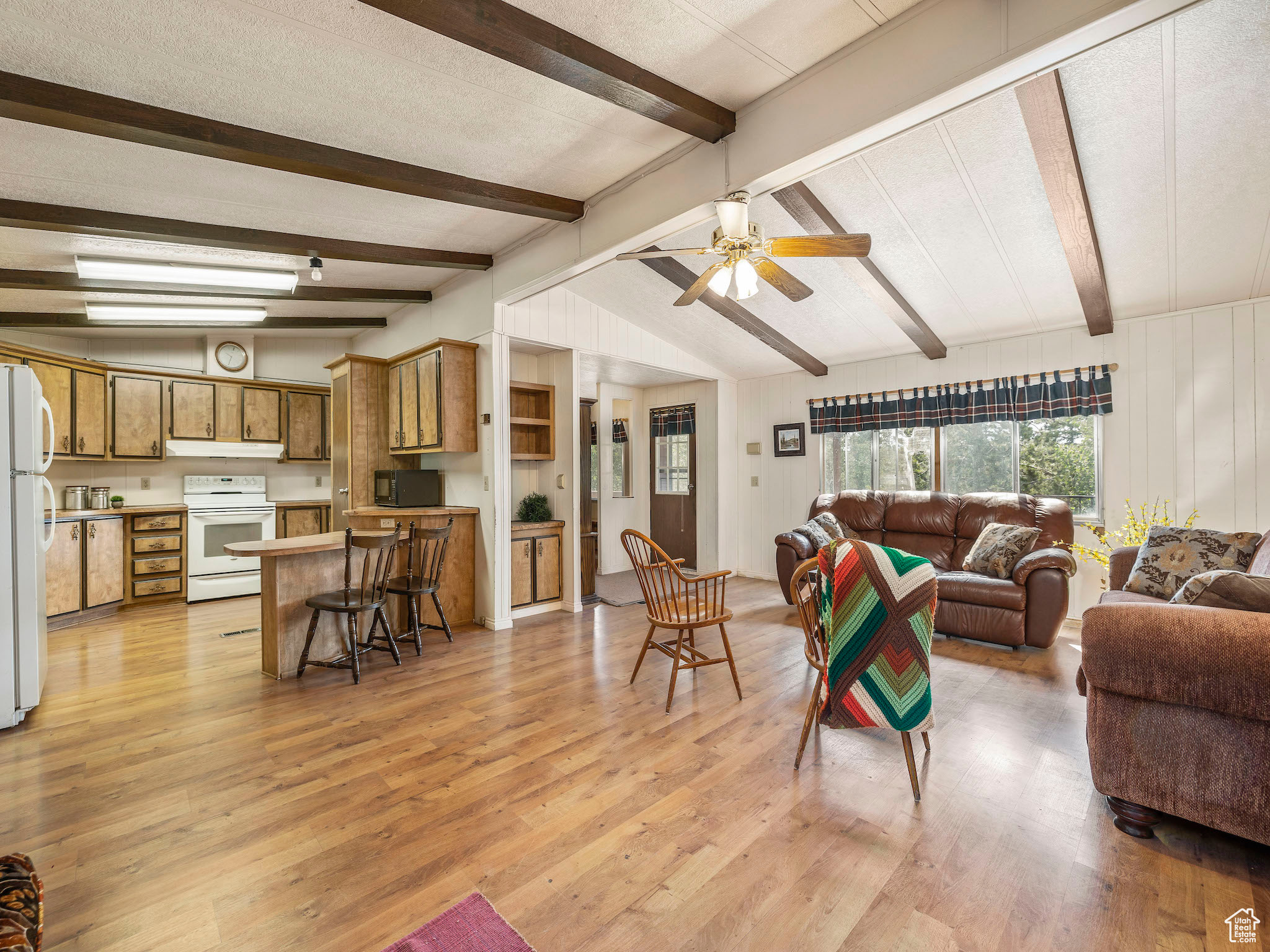 Living room with ceiling fan, light hardwood / wood-style floors, and vaulted ceiling with beams