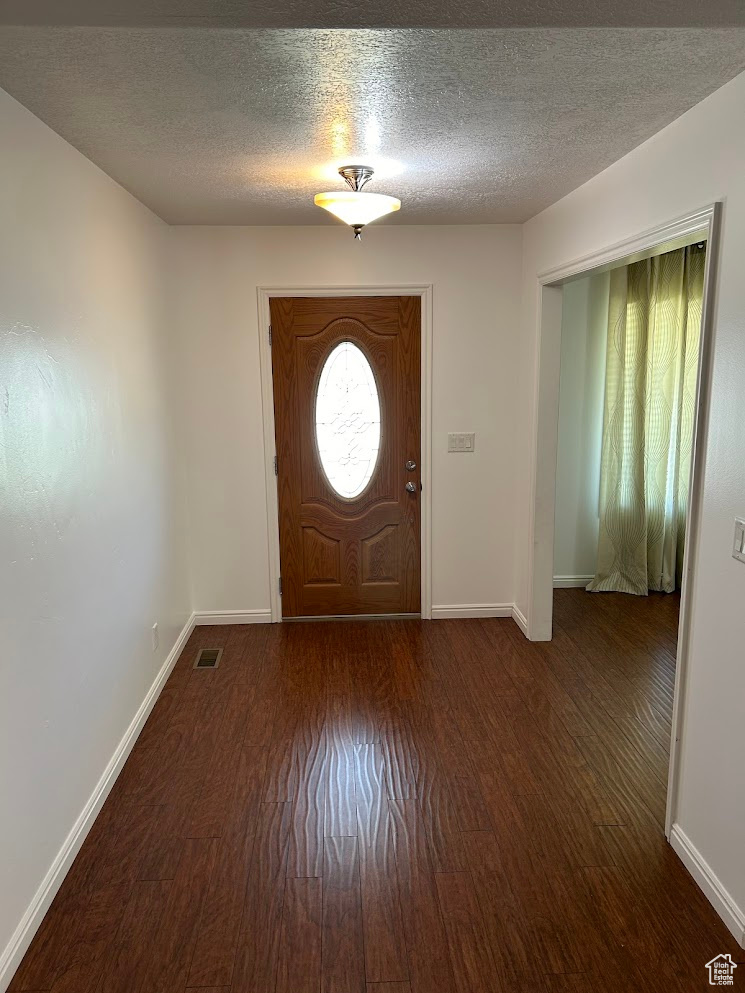 Foyer entrance featuring a textured ceiling and dark hardwood / wood-style flooring