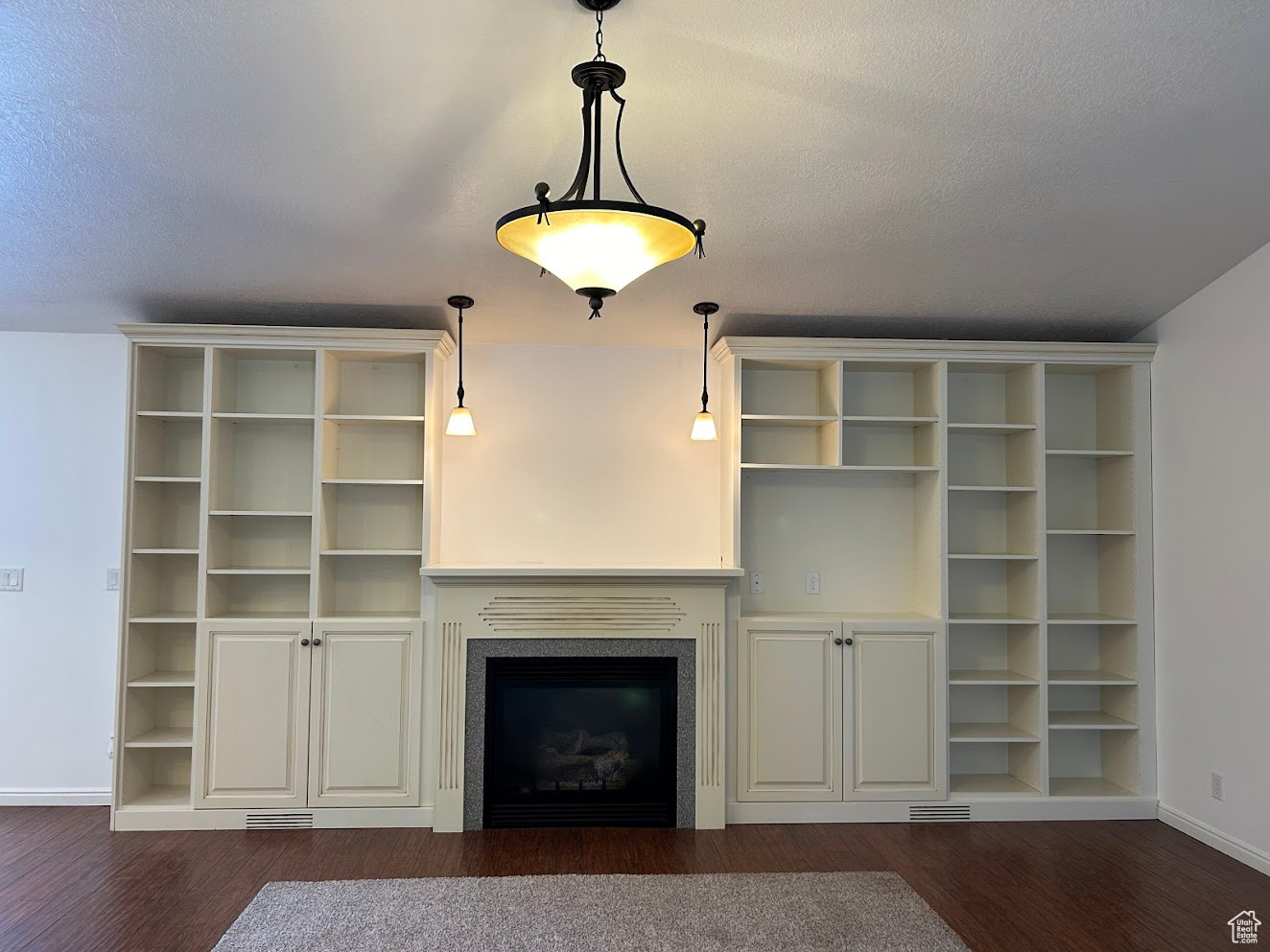 Unfurnished living room featuring dark wood-type flooring and a textured ceiling